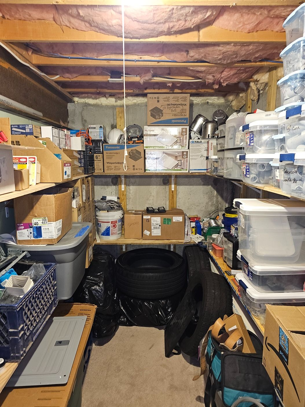 Cluttered basement storage room packed with boxes, bins, and household supplies on shelves and floor.
