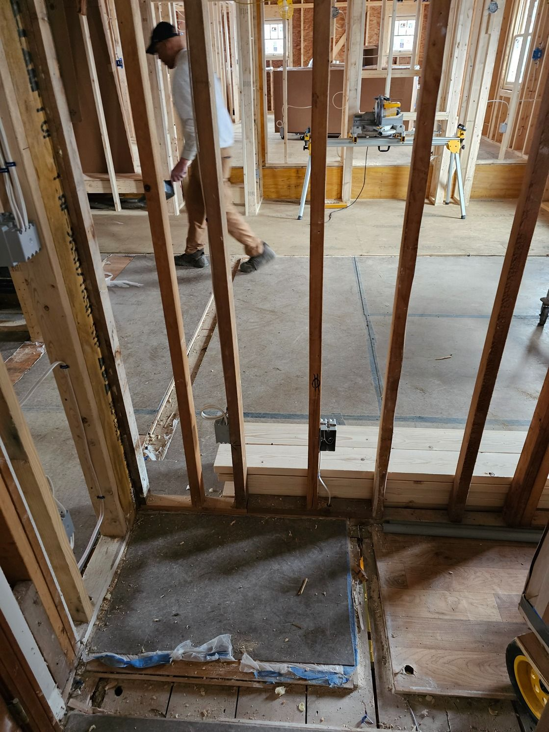 Construction framing with exposed studs and a worker in a partially finished room