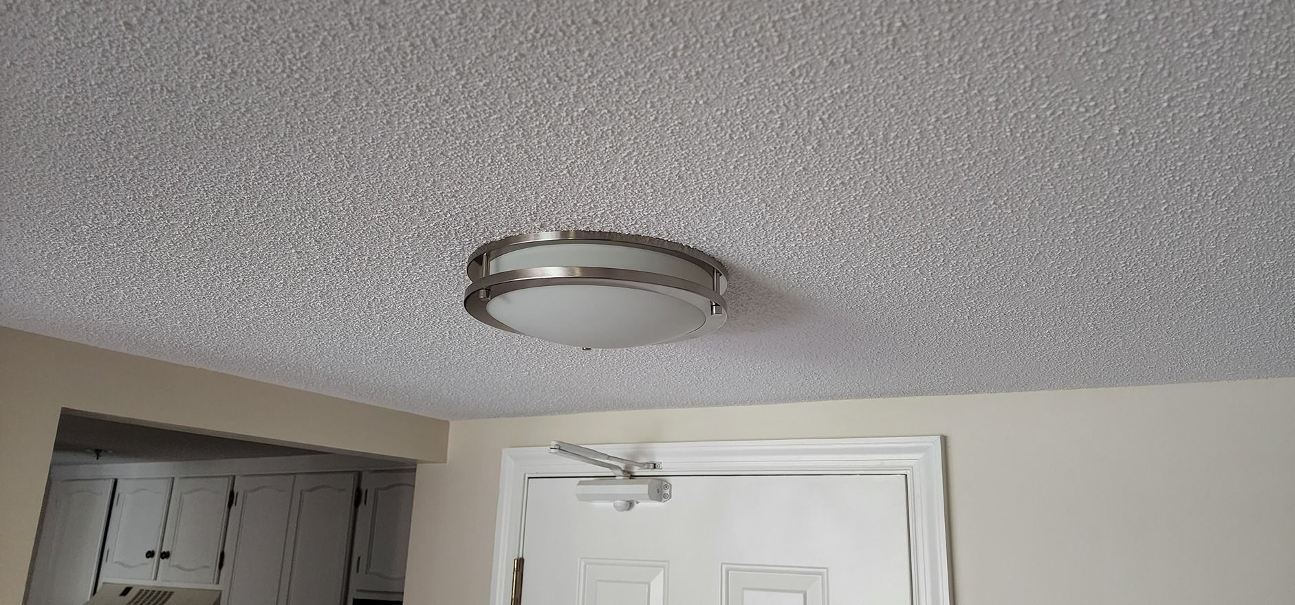 Ceiling light fixture above a white door in a beige hallway