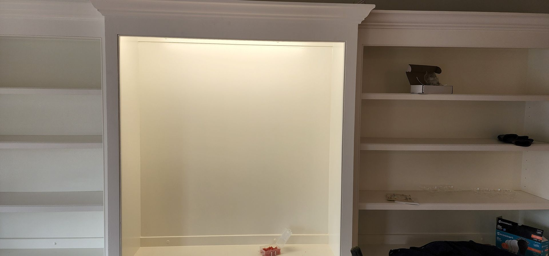 Built-in white bookshelves flanking a recessed wall niche with soft lighting