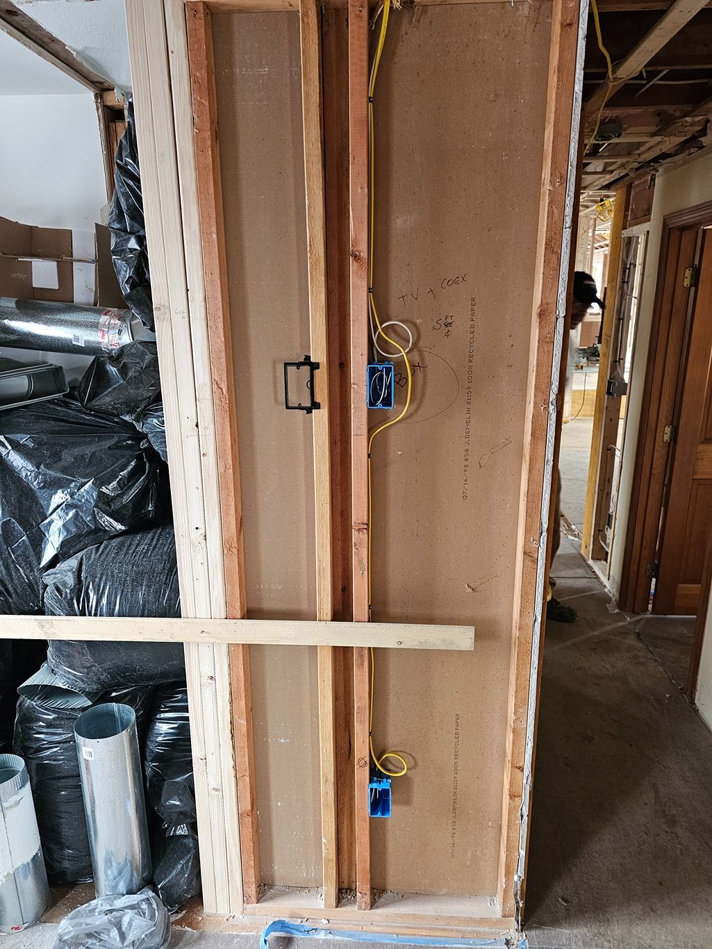 Unfinished interior wall framing with exposed electrical boxes and wiring in a construction site.