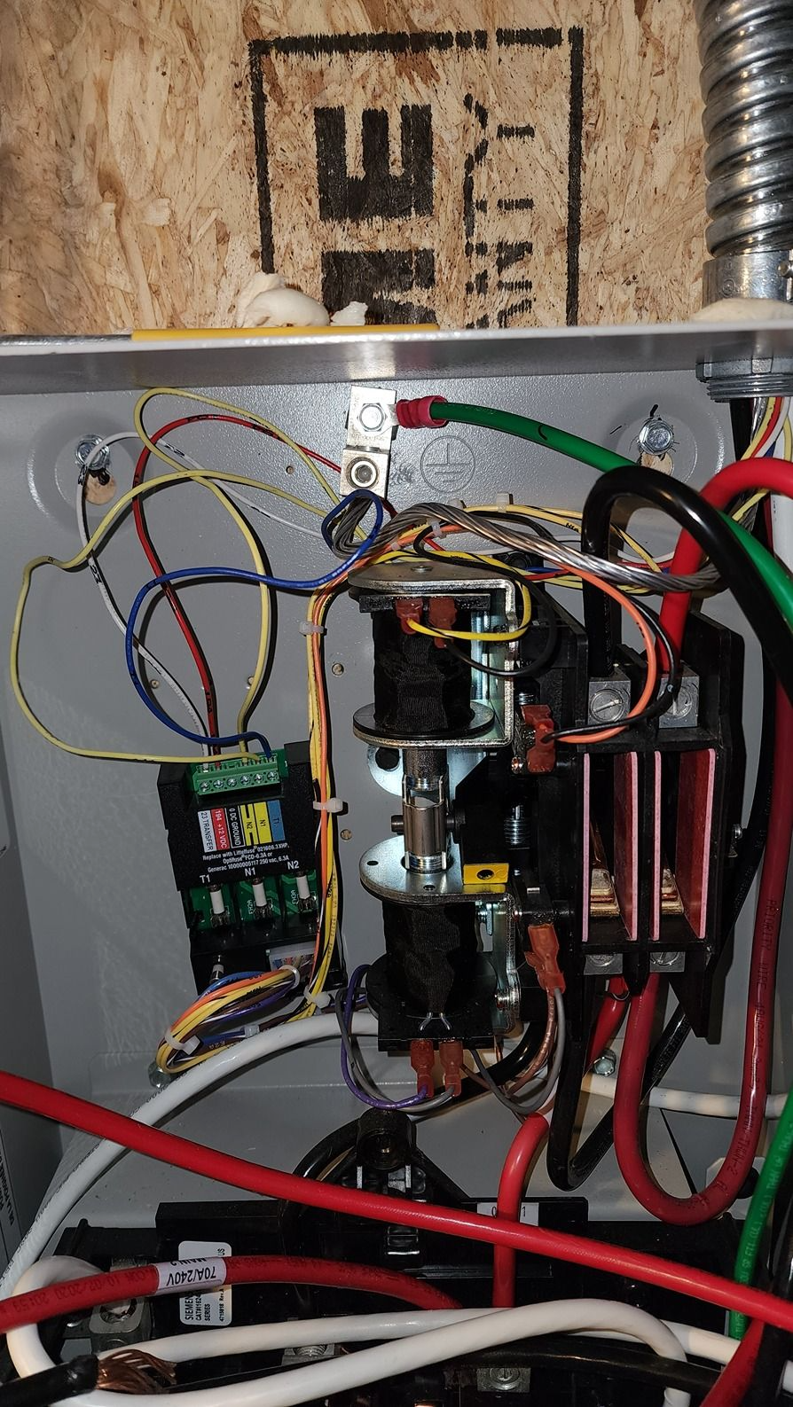 Close-up of an electrical control box with colored wires, relays, and components mounted inside.