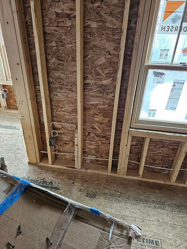 Interior wall framing under construction with exposed studs, insulation, and a window opening