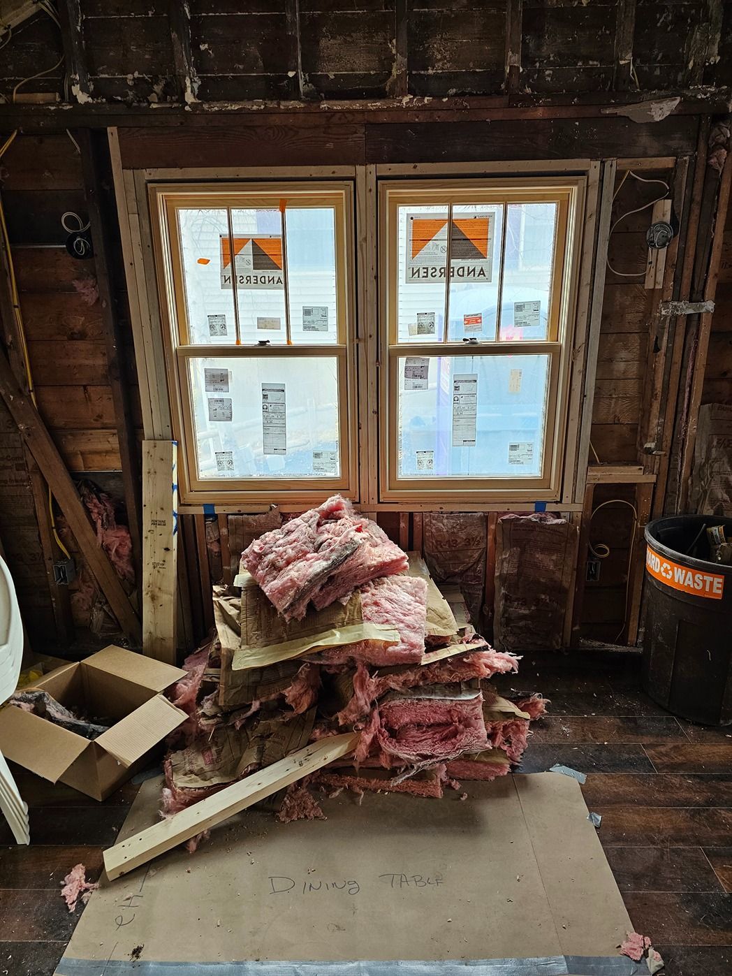 Damaged room with exposed walls, window, and pile of insulation and debris on the floor
