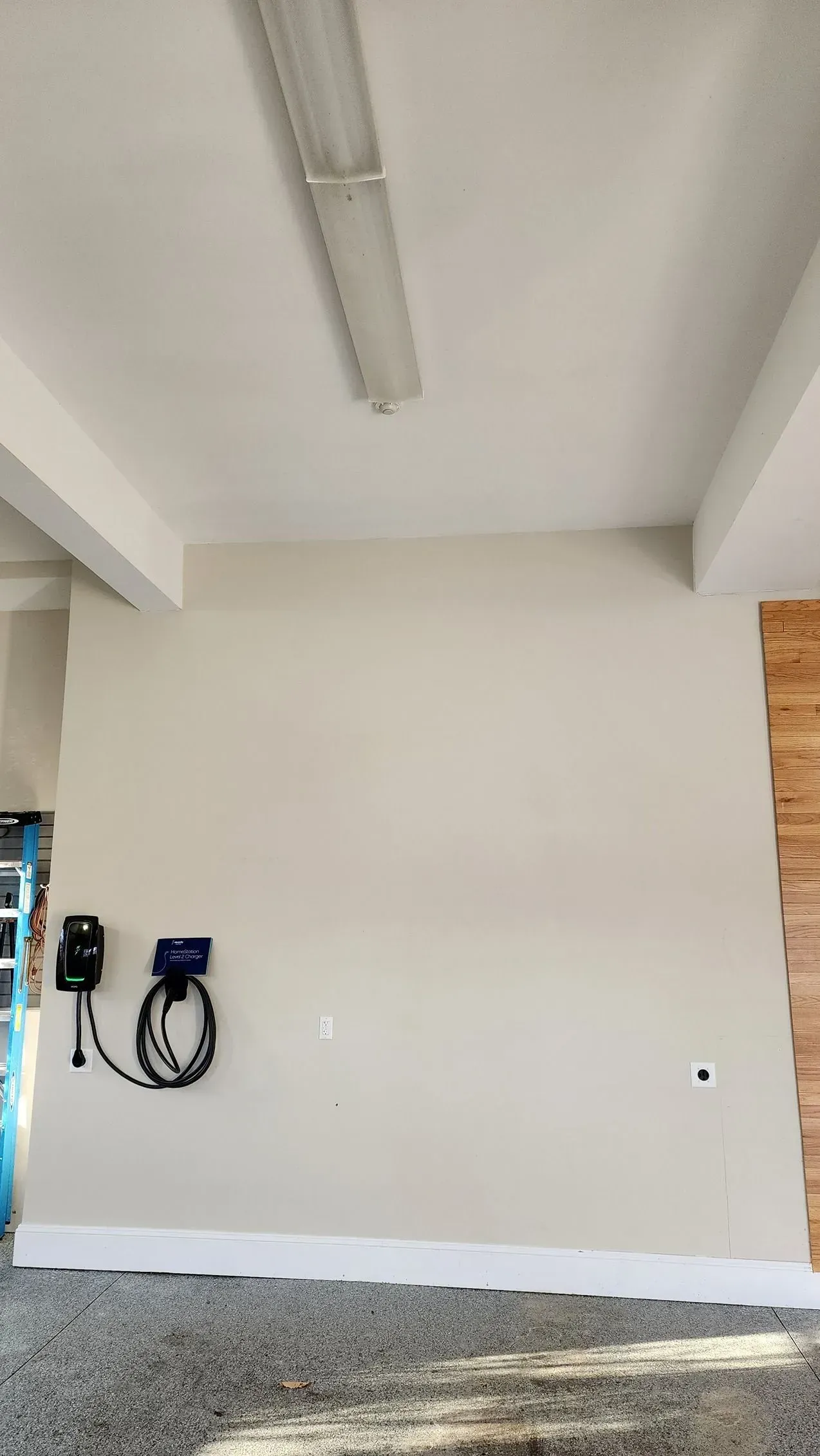 Empty white interior wall with mounted electrical boxes and coiled cables, plus a ceiling light overhead