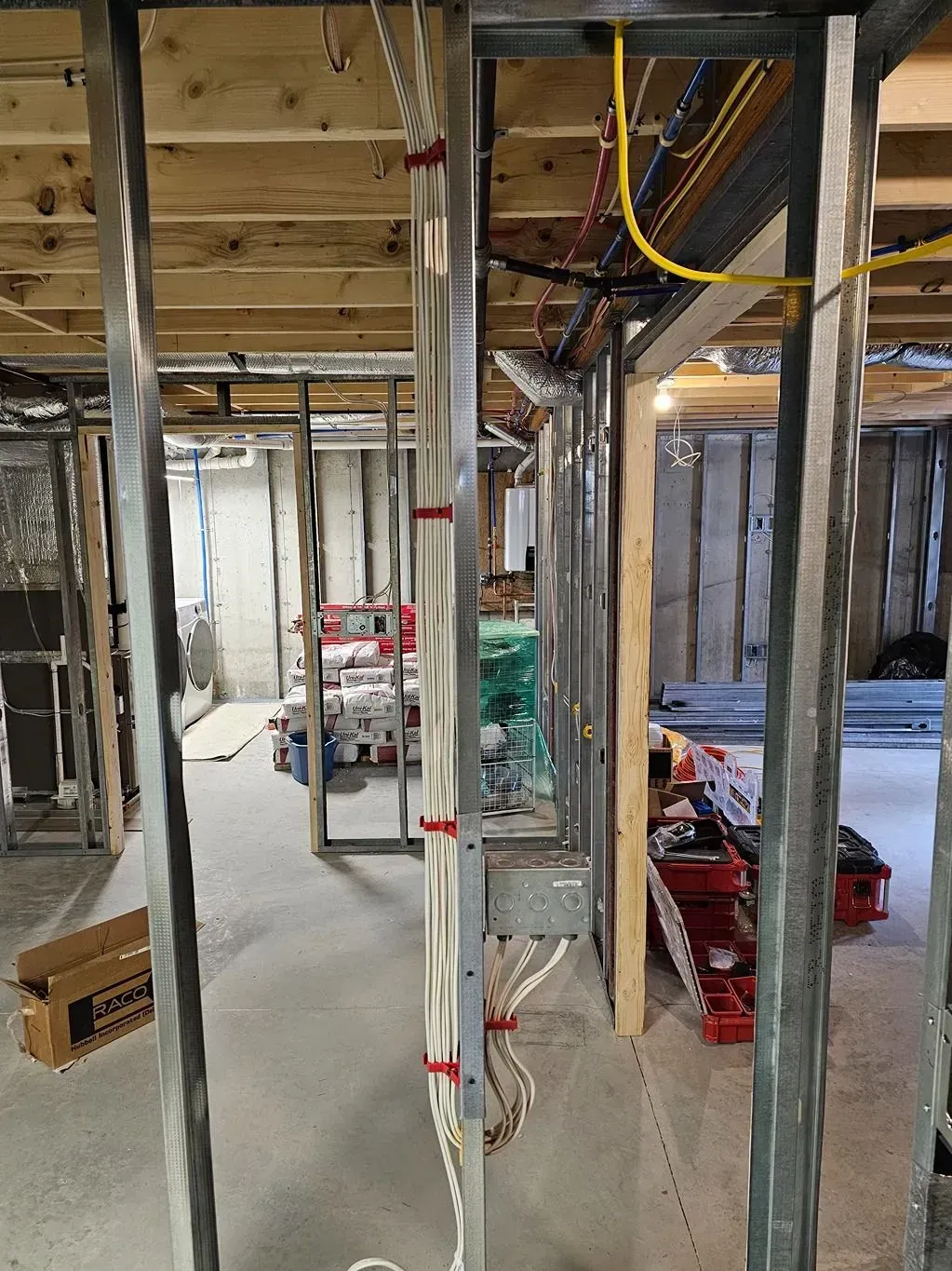 Basement construction site with exposed beams, wiring, and scattered tools and materials