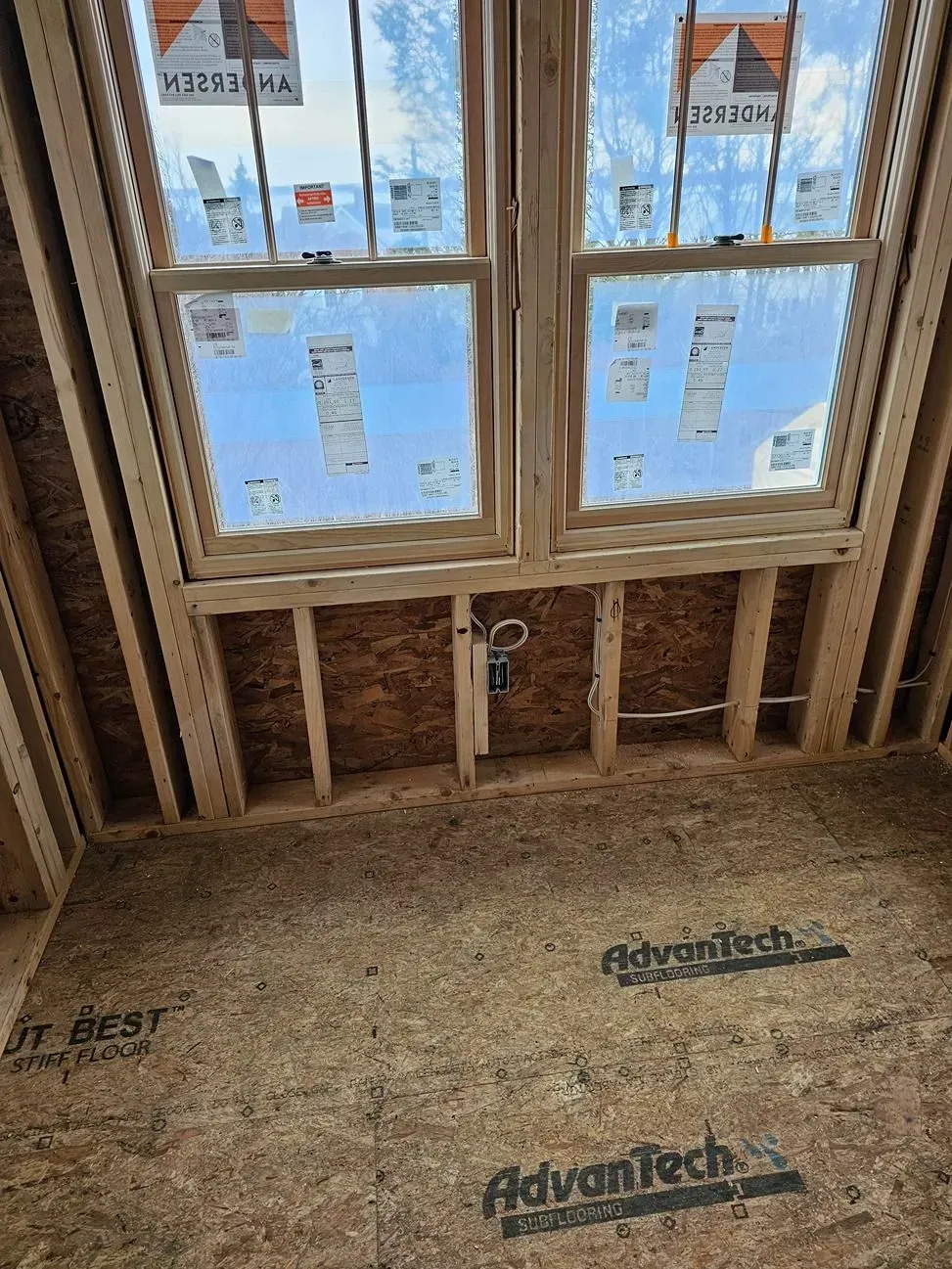 Unfinished room with window, exposed studs, and wood subfloor under construction.