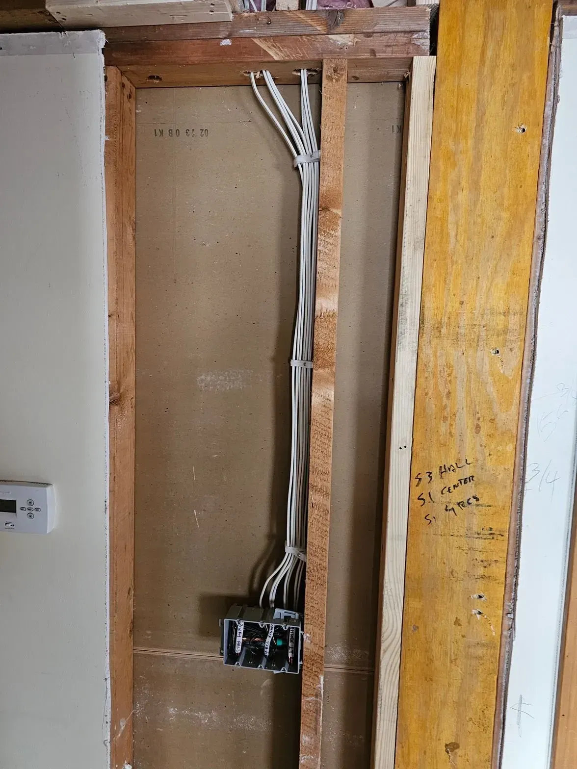 Exposed electrical wiring and breaker box in a wall opening during home renovation