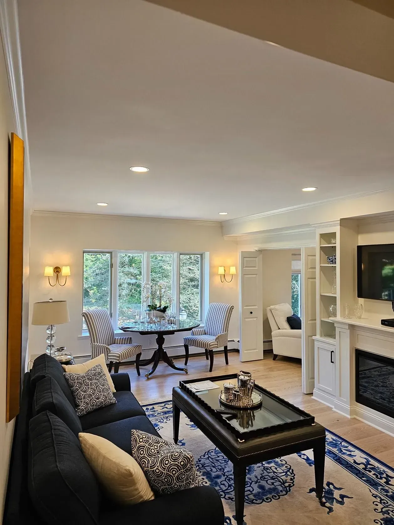 Bright living room with black sofa, coffee table, fireplace, TV, and sliding doors to a patio.