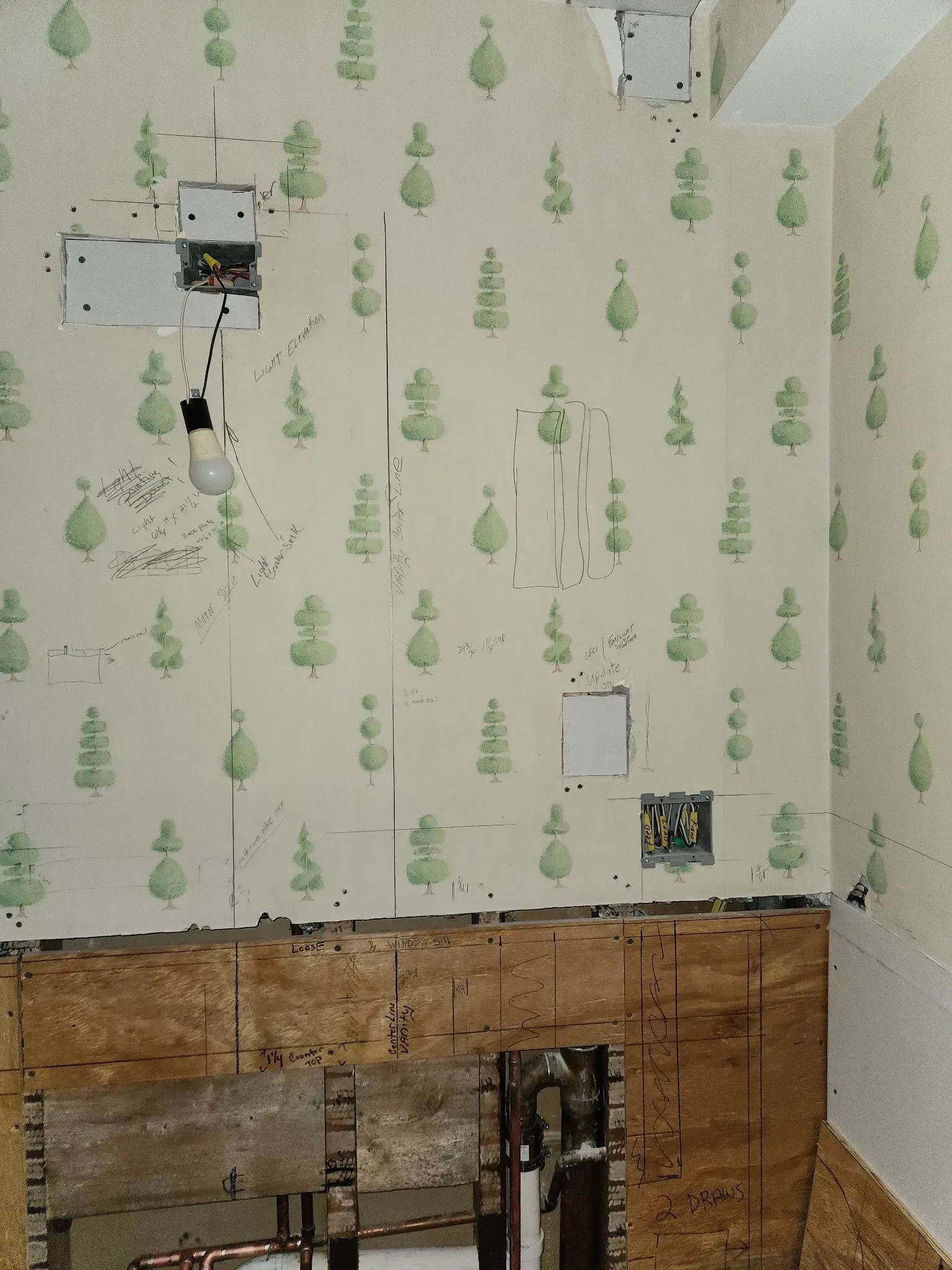 Partially renovated room with floral wallpaper, exposed wall framing, and electrical fixtures on the wall