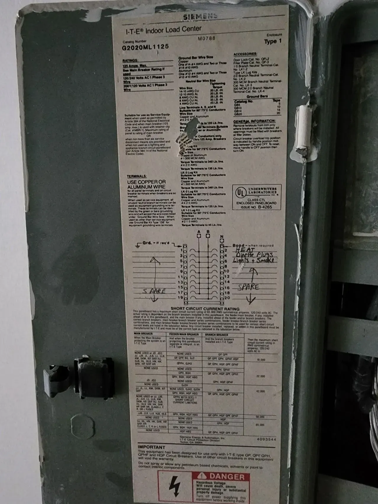 Gray electrical panel door with manufacturer label and wiring diagram inside side compartment.