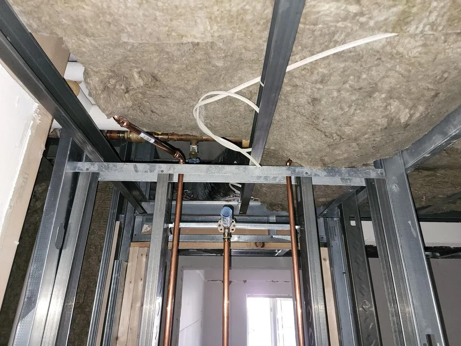 Ceiling view of exposed metal framing and rough insulation in an unfinished room