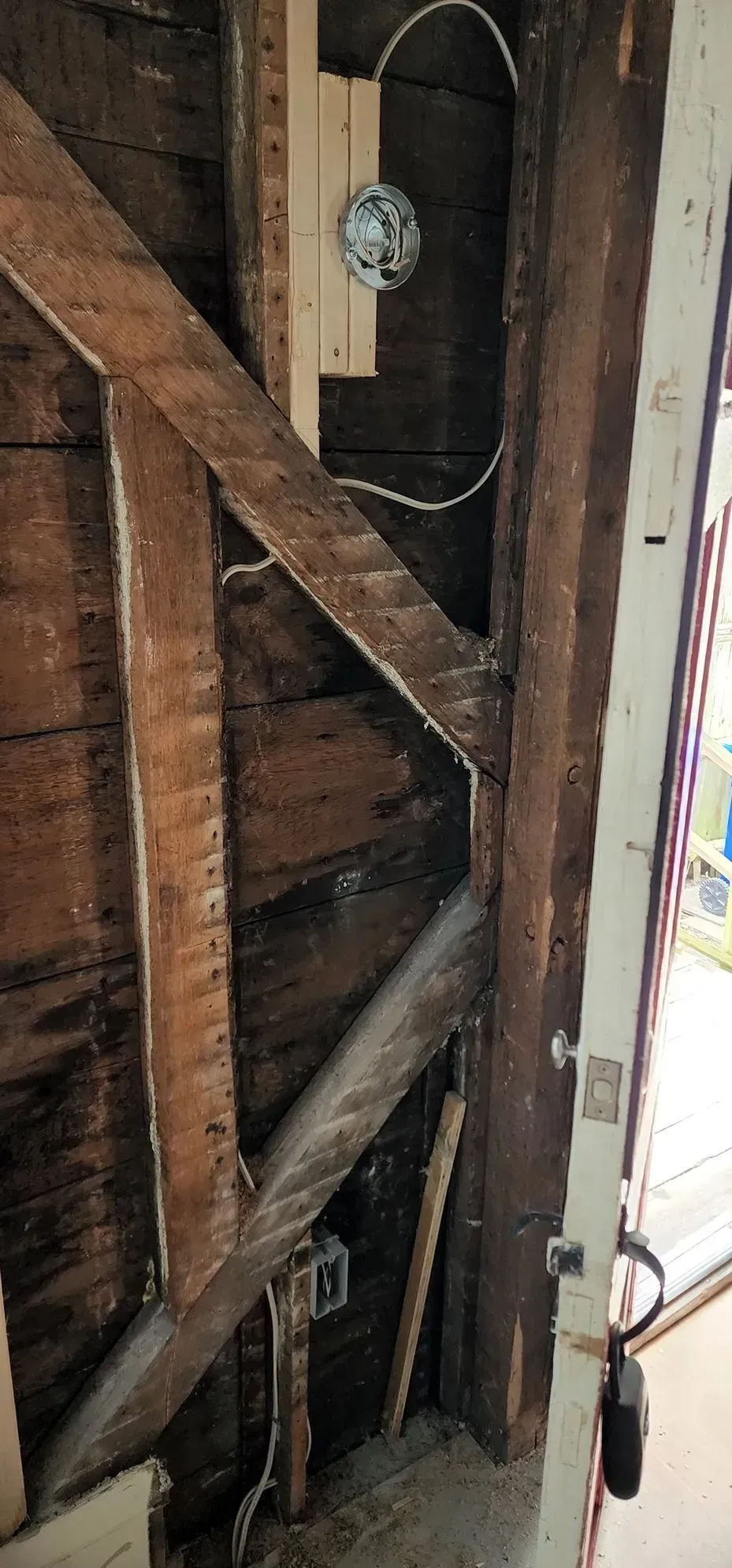 Exposed wooden wall framing with a round gauge or meter mounted near the center.