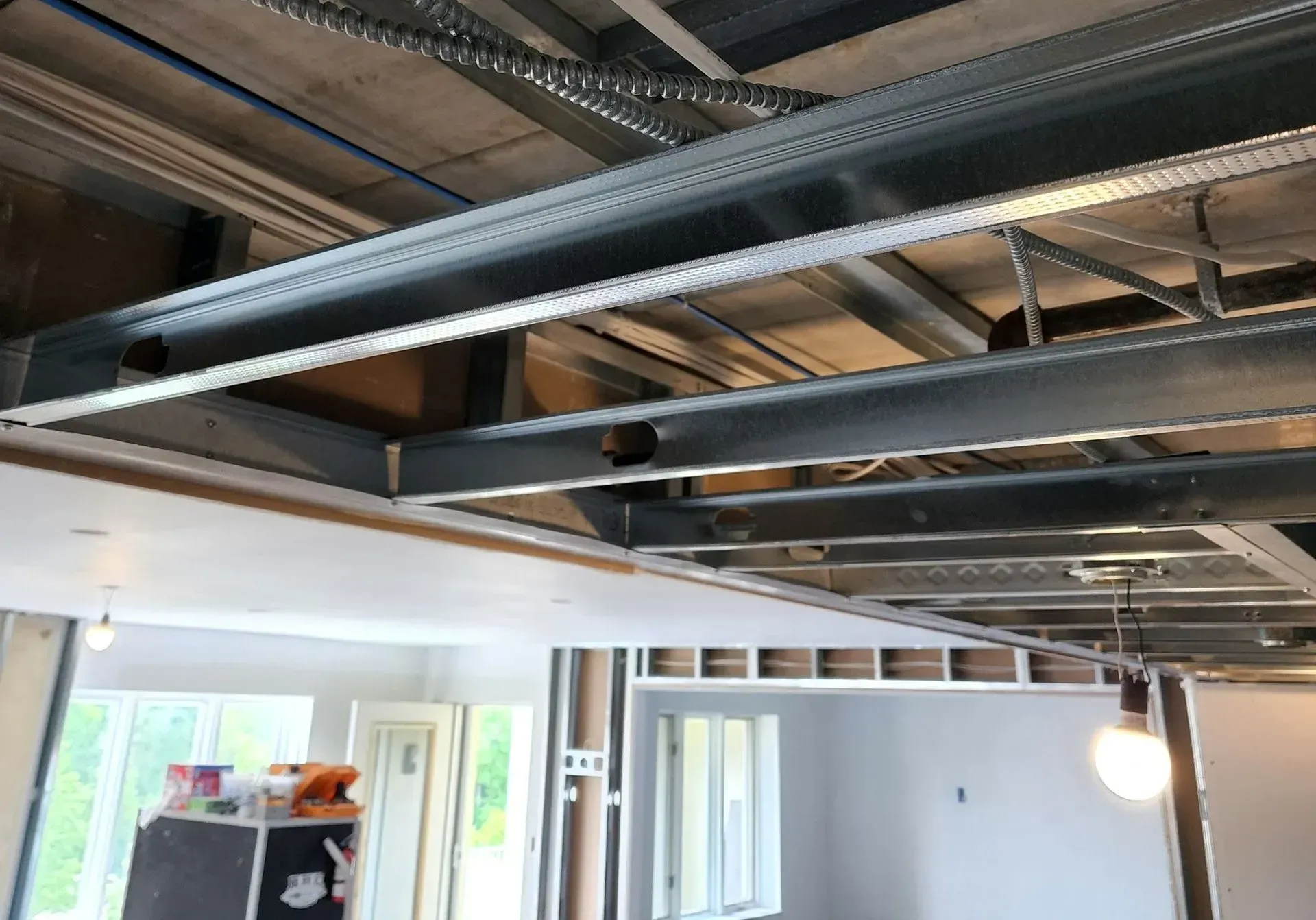 Exposed ceiling with metal ductwork and wiring in an unfinished indoor renovation area.