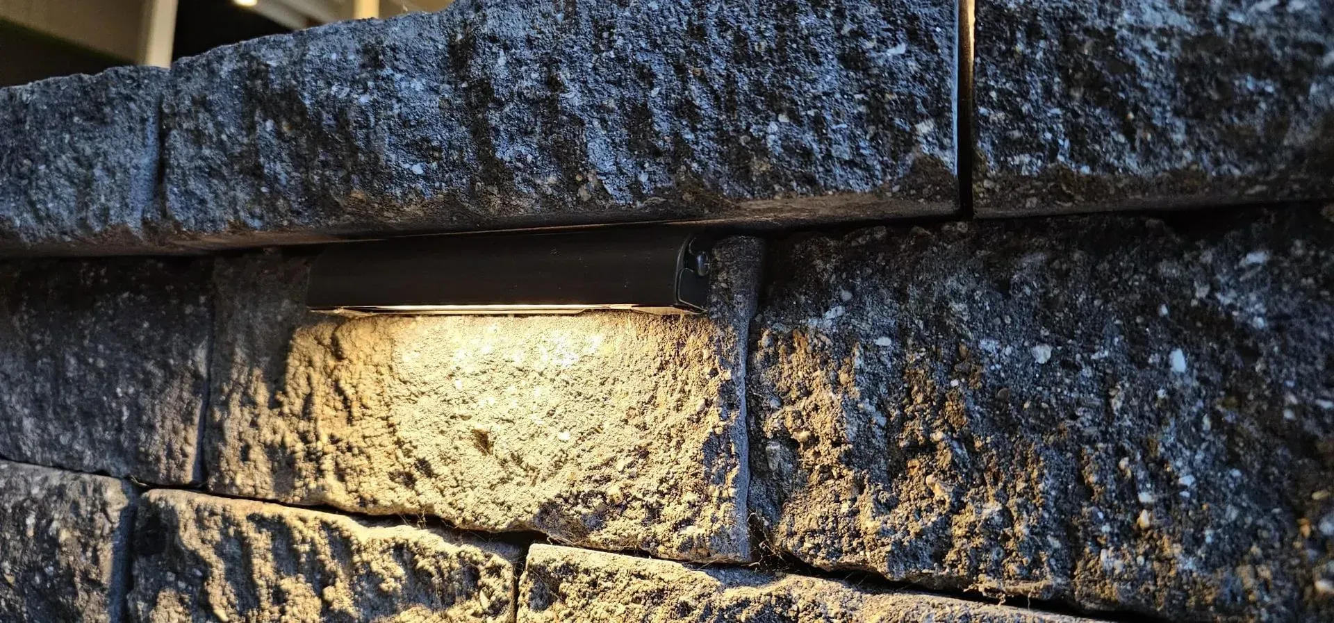 Sunlit stone wall with rough stacked blocks and dark shadows
