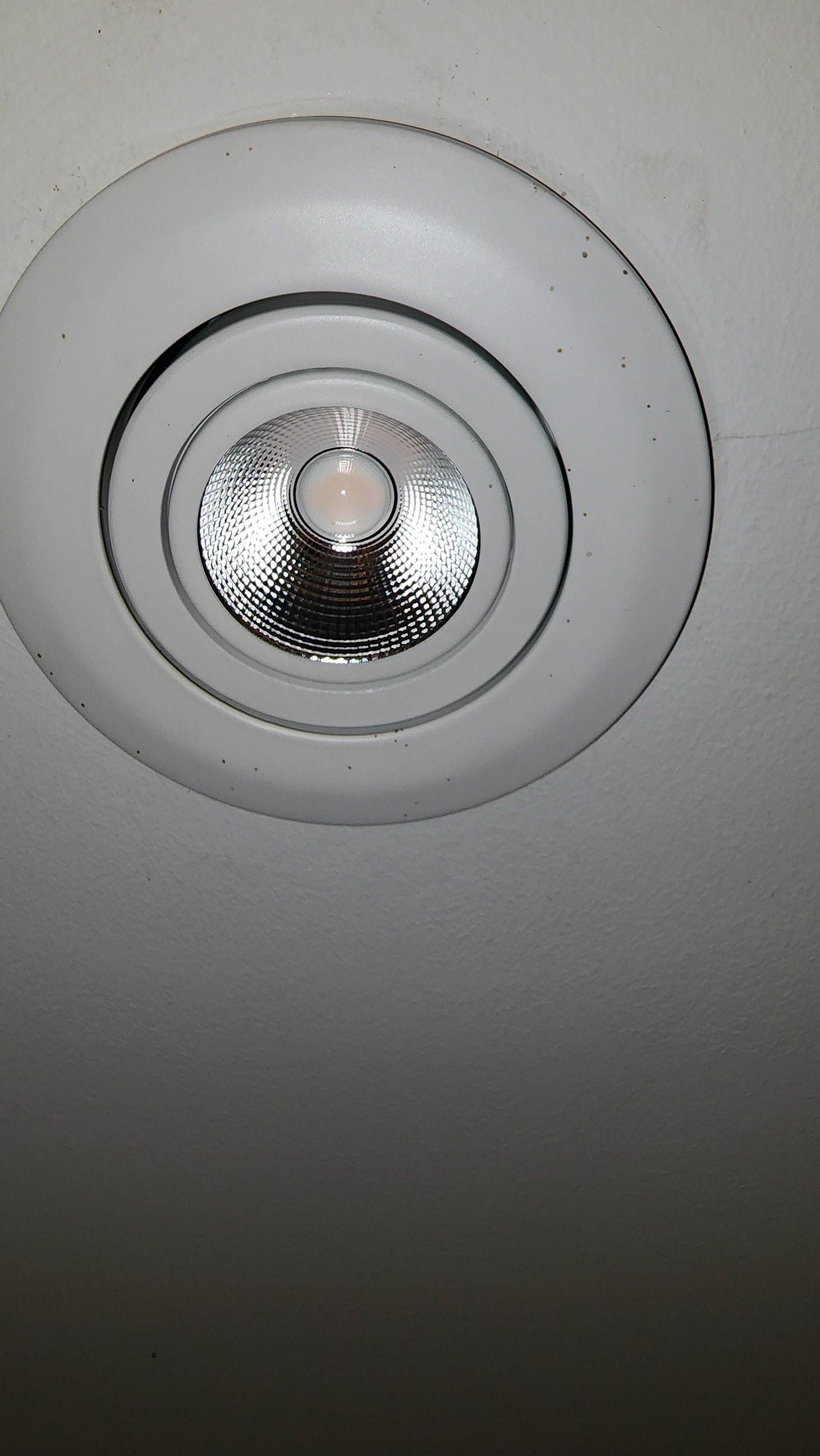 Recessed ceiling spotlight with white trim and reflective silver interior, viewed from below