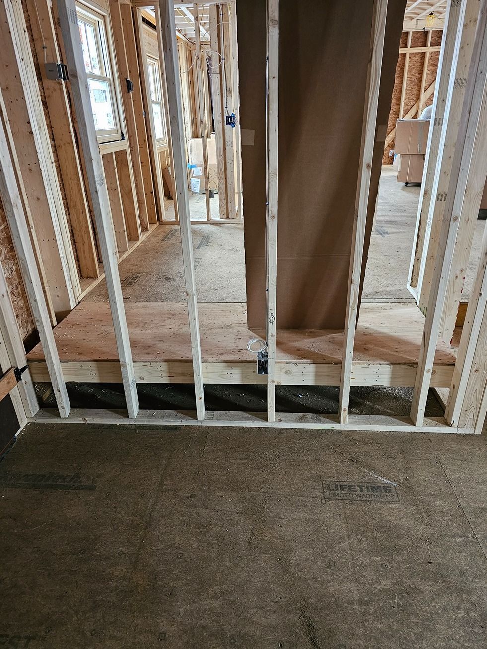 Unfinished interior with exposed wall studs, a doorway opening, and a temporary white safety gate.