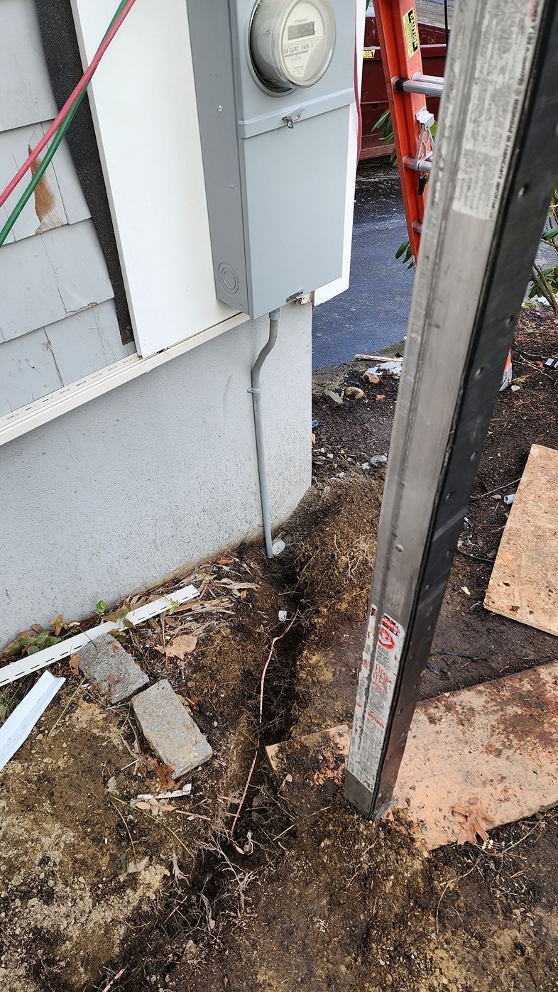 Narrow outdoor gap beside a house with dirt, debris, utility box, and a leaning metal post.