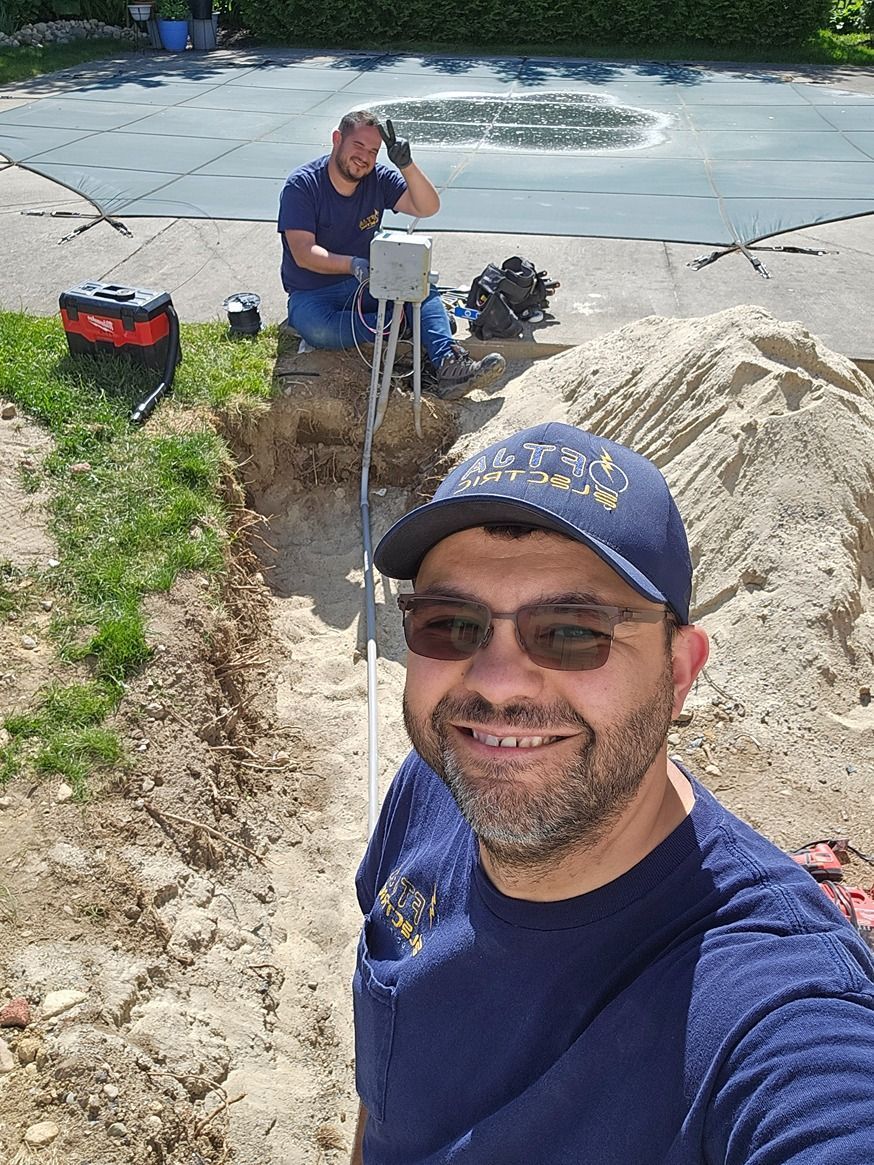 Man smiling near a shallow trench at a beach cleanup, with another person and equipment in the background
