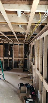Unfinished interior room with exposed wooden framing, wiring, and construction tools on the floor.