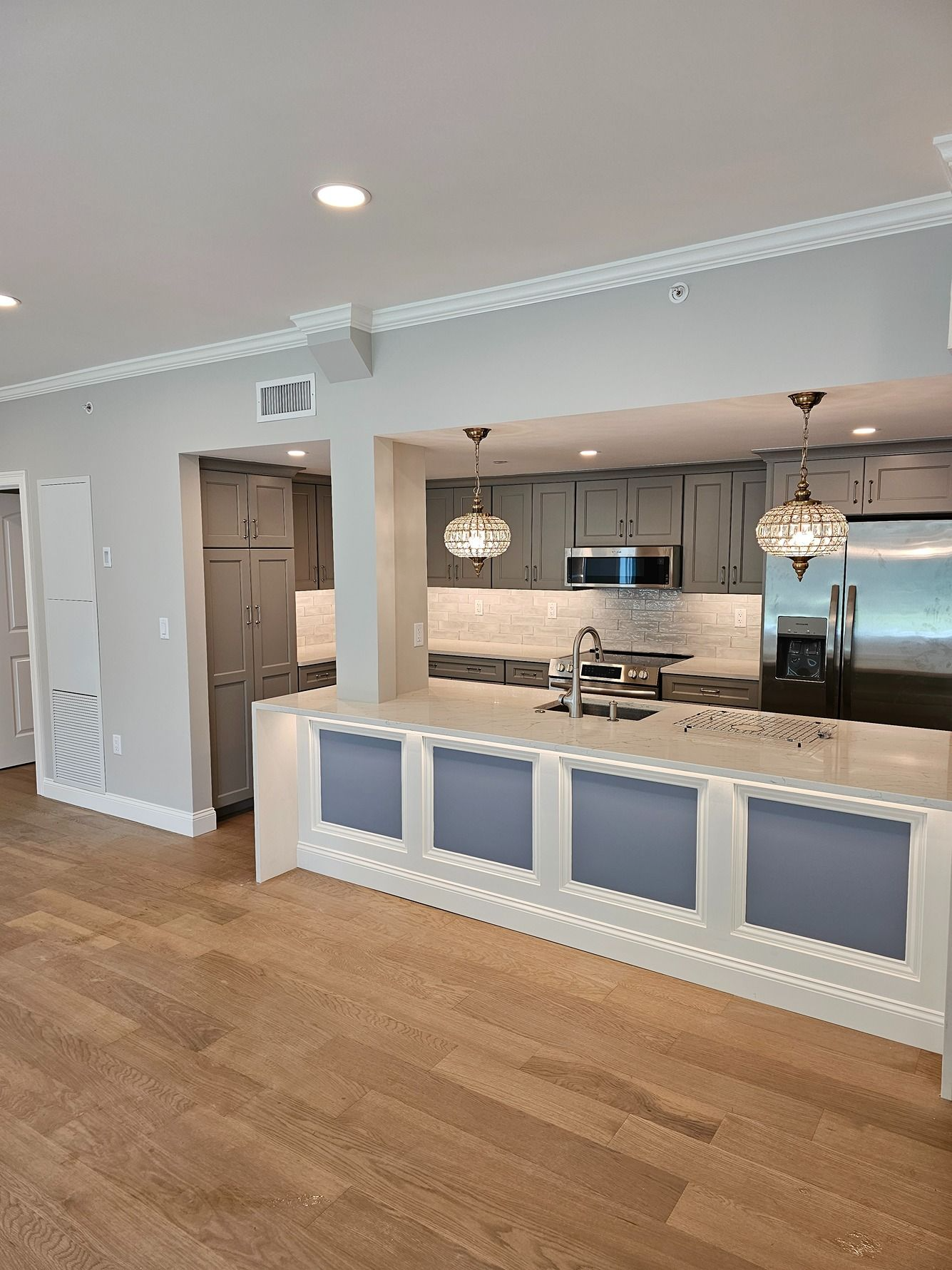 Bright open kitchen with blue island panels, white cabinetry, and hardwood floors in a modern home