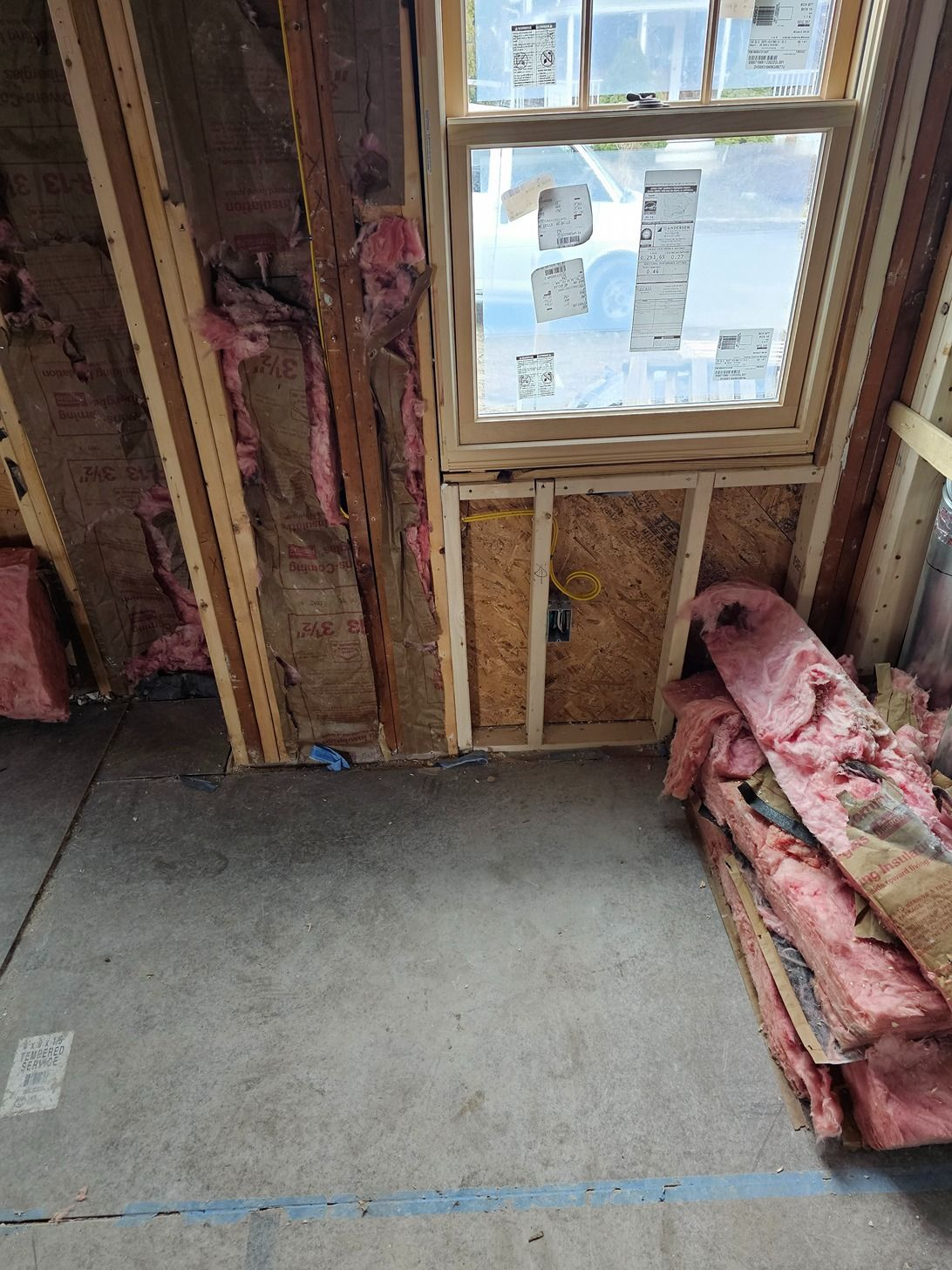 Unfinished room with exposed insulation, a window, and a concrete floor.