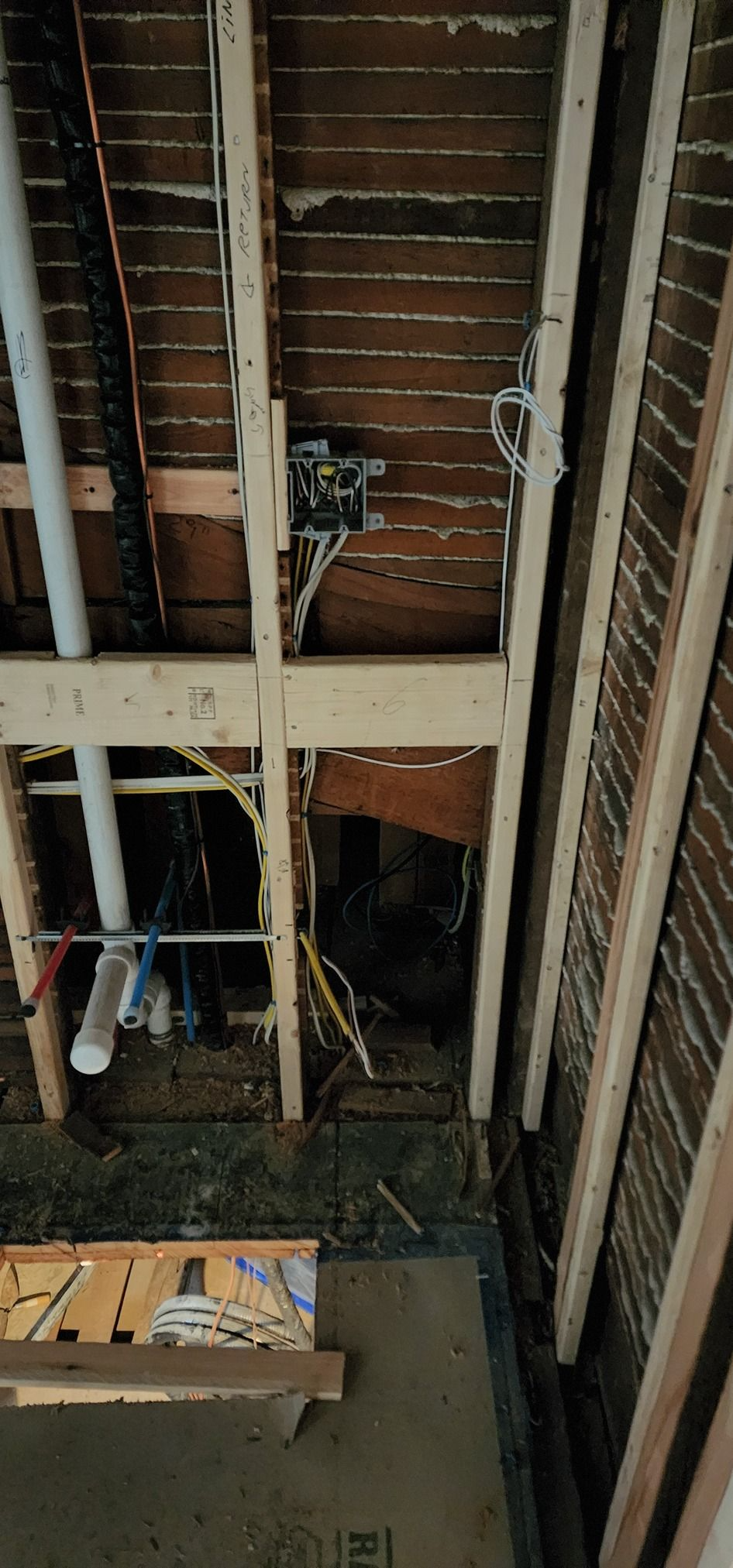 Exposed wall framing and wiring inside a room under renovation, with debris on the floor.