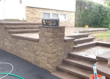 Stone steps and retaining walls leading to a building entrance, with a small sign on the wall.