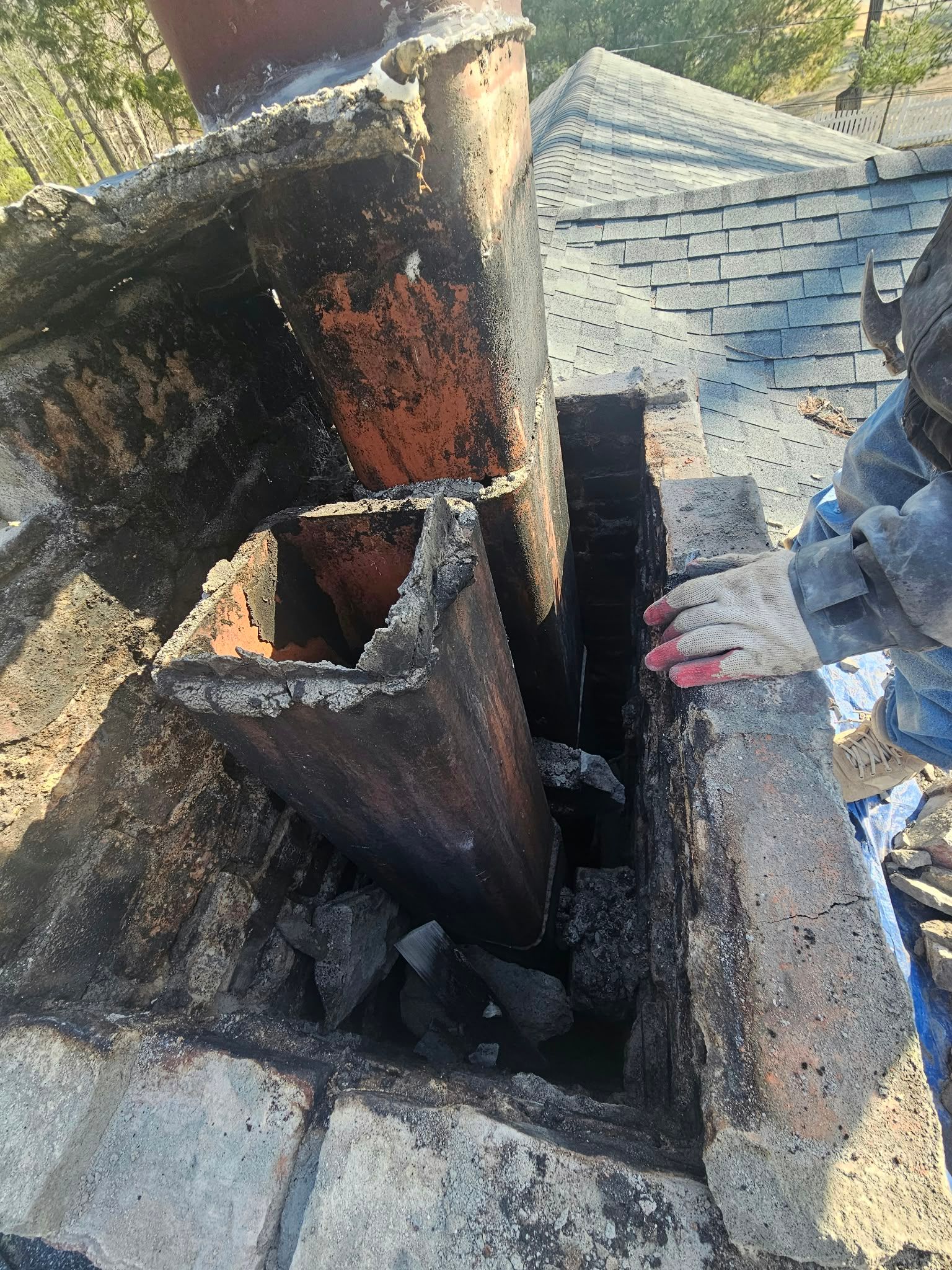 Charred rooftop chimney flue and fire-damaged masonry around a collapsed opening