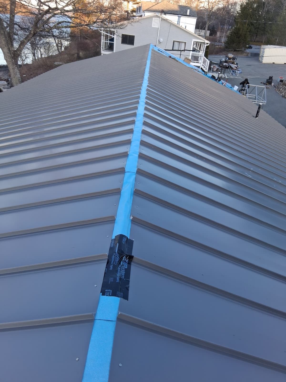Blue roof seam on a metal rooftop, with a city view in the background