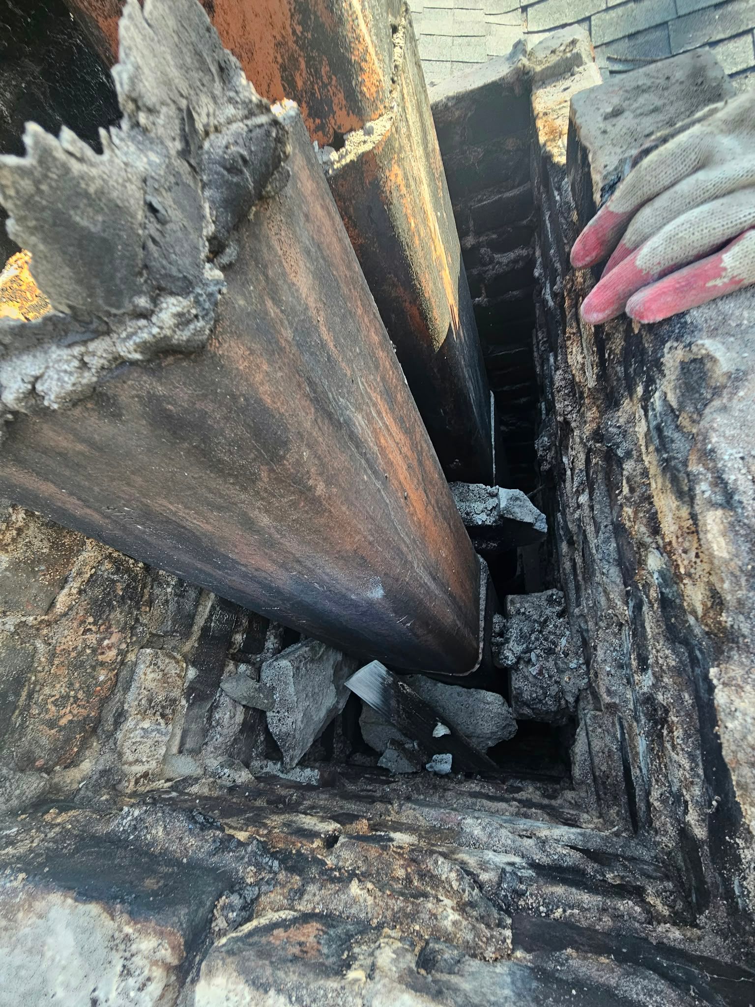 Close-up of charred wood with a narrow crack, showing a hand holding a piece of debris.
