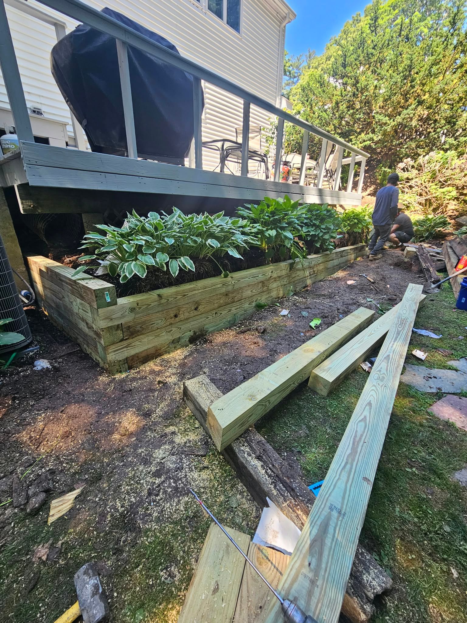 Damaged wooden ramp and broken boards beside a house porch with a person inspecting the area