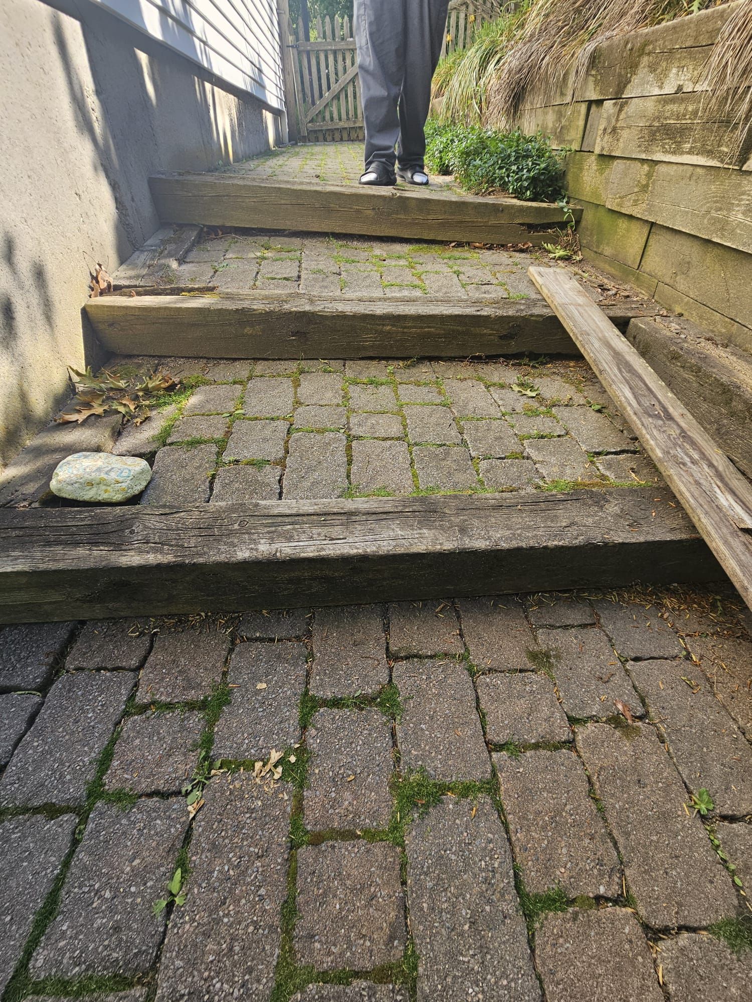 Steep outdoor stone steps with mossy pavers between tall stone walls and a person at the top