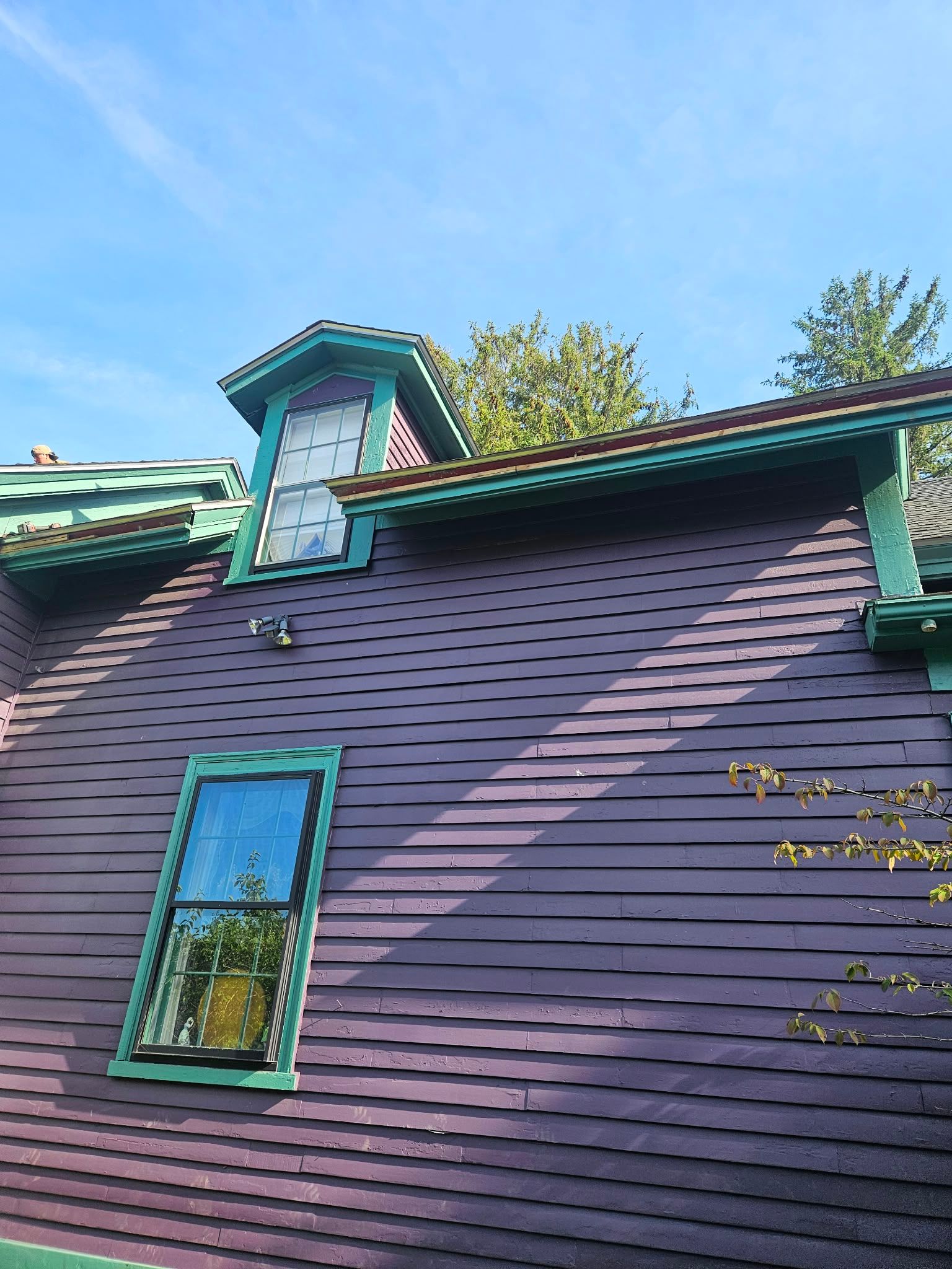 Purple house exterior with teal-trimmed dormer windows and blue sky above