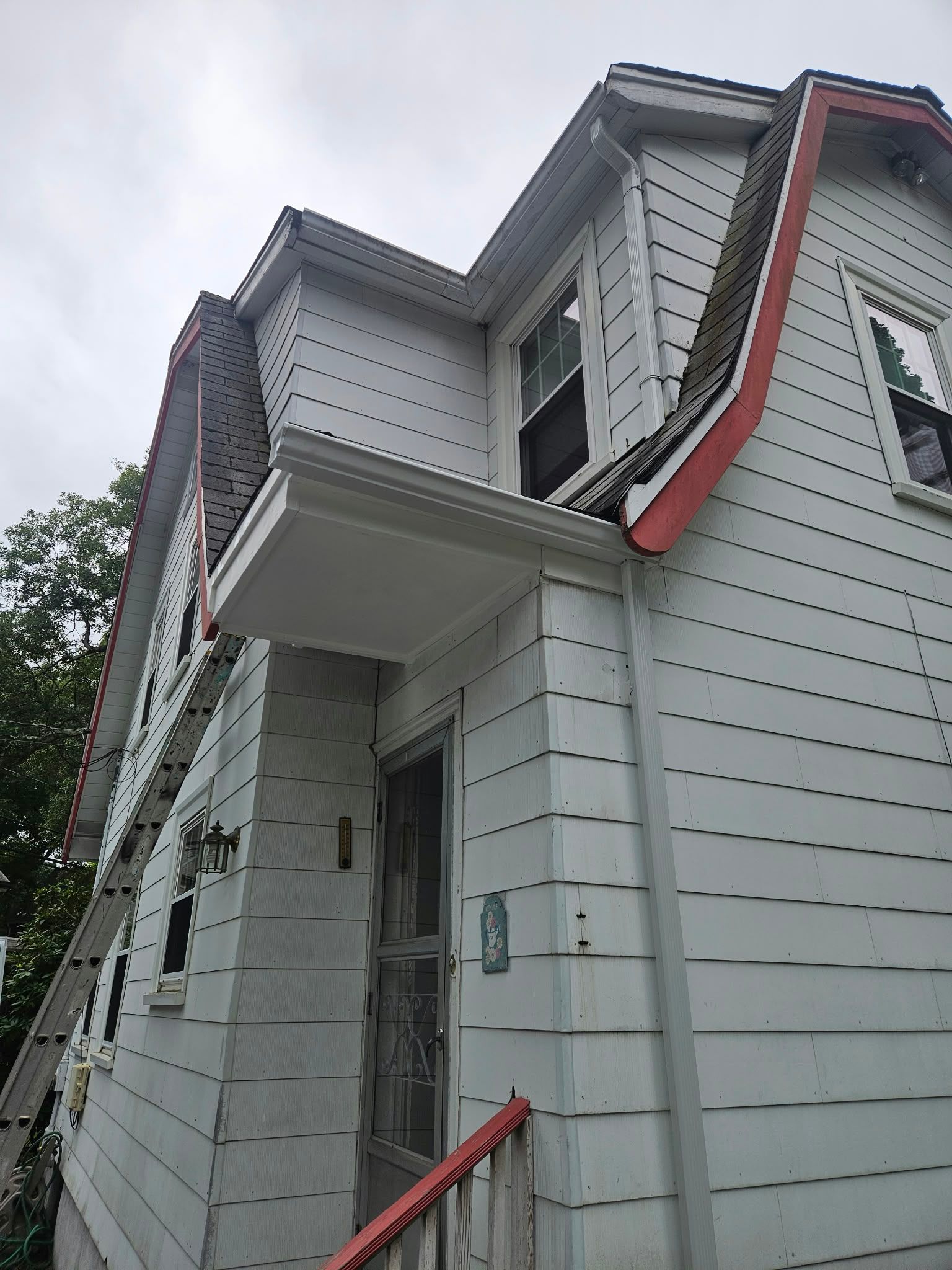 White house exterior with red trim and front steps, viewed from below
