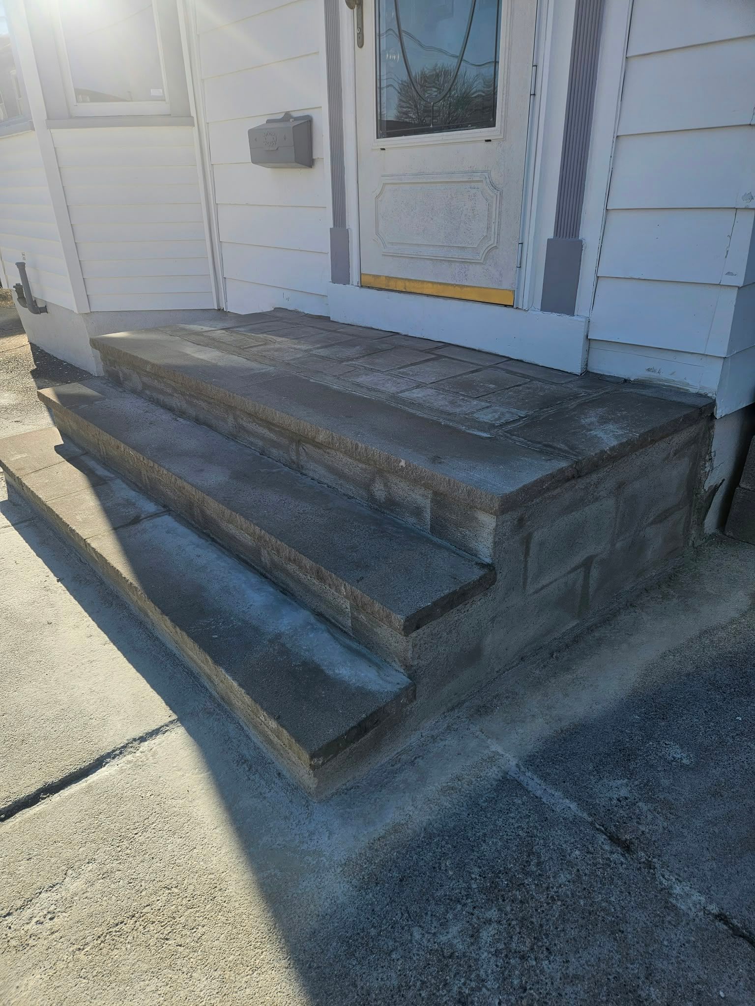 Concrete front porch steps leading to a white door on a house