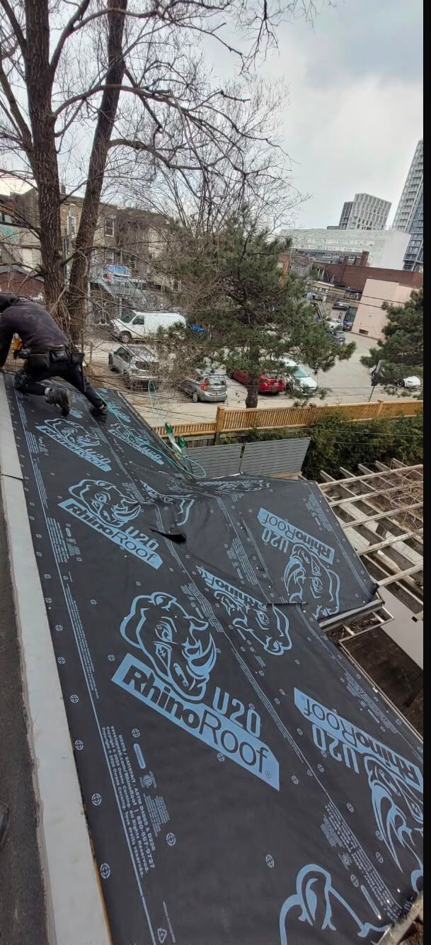 Person painting blue designs on a large black rooftop panel in a snowy outdoor setting