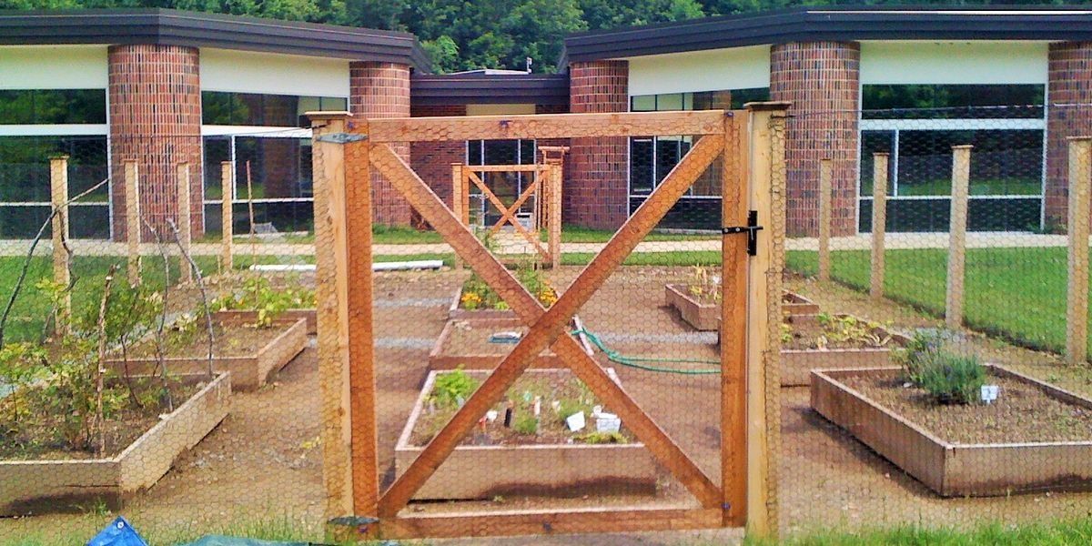 A wooden gate is surrounded by planters in a garden.