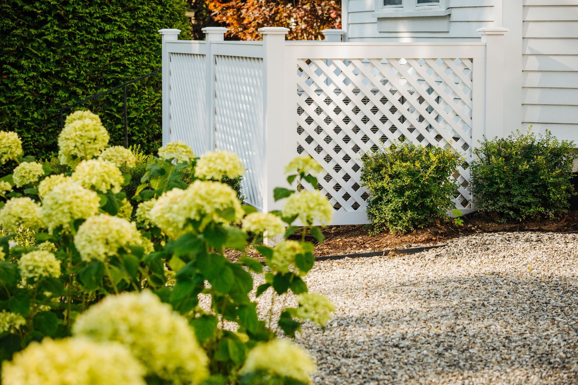 A white fence with flowers in front of a house.