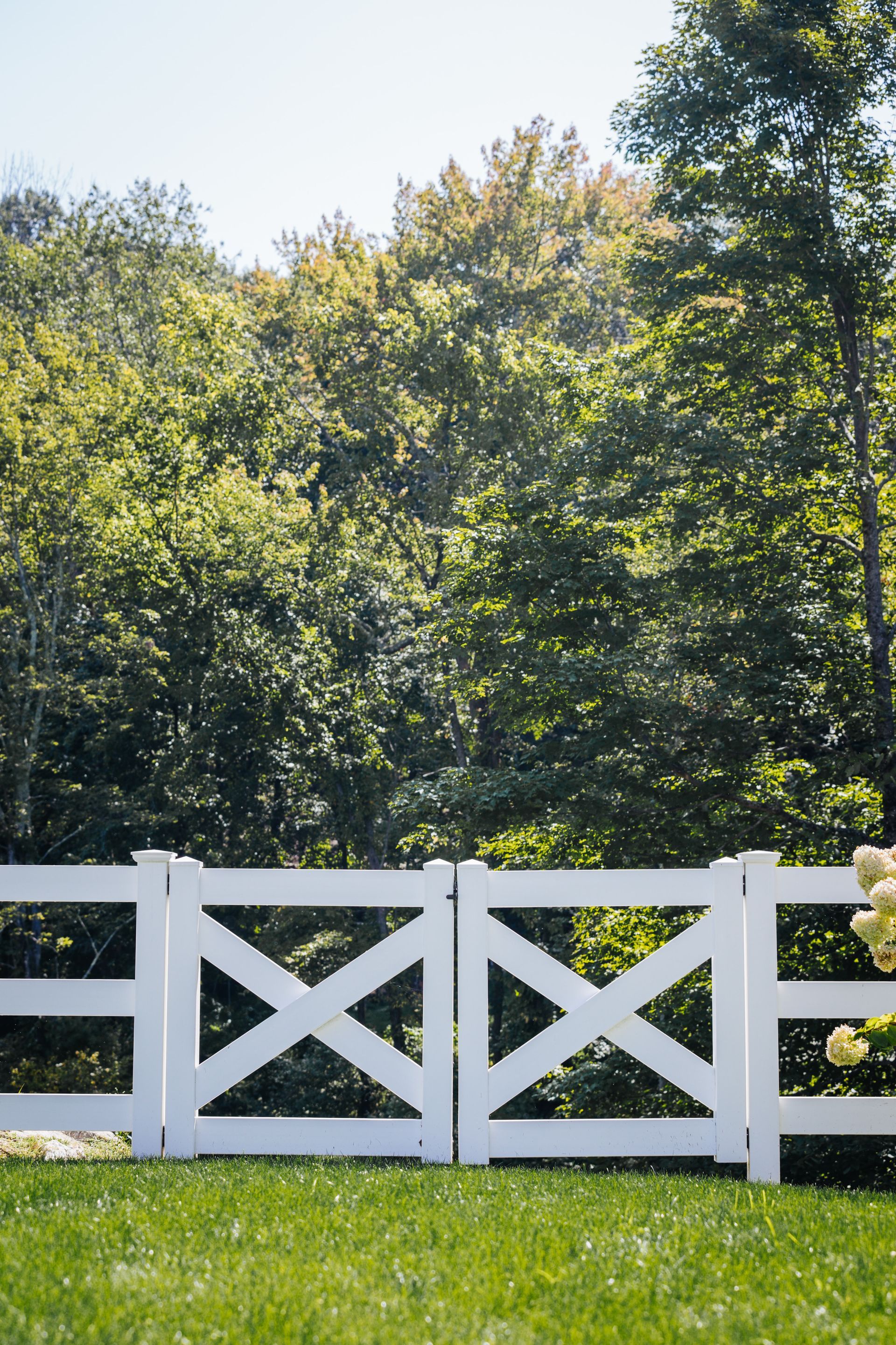A white fence is sitting in the middle of a lush green field.