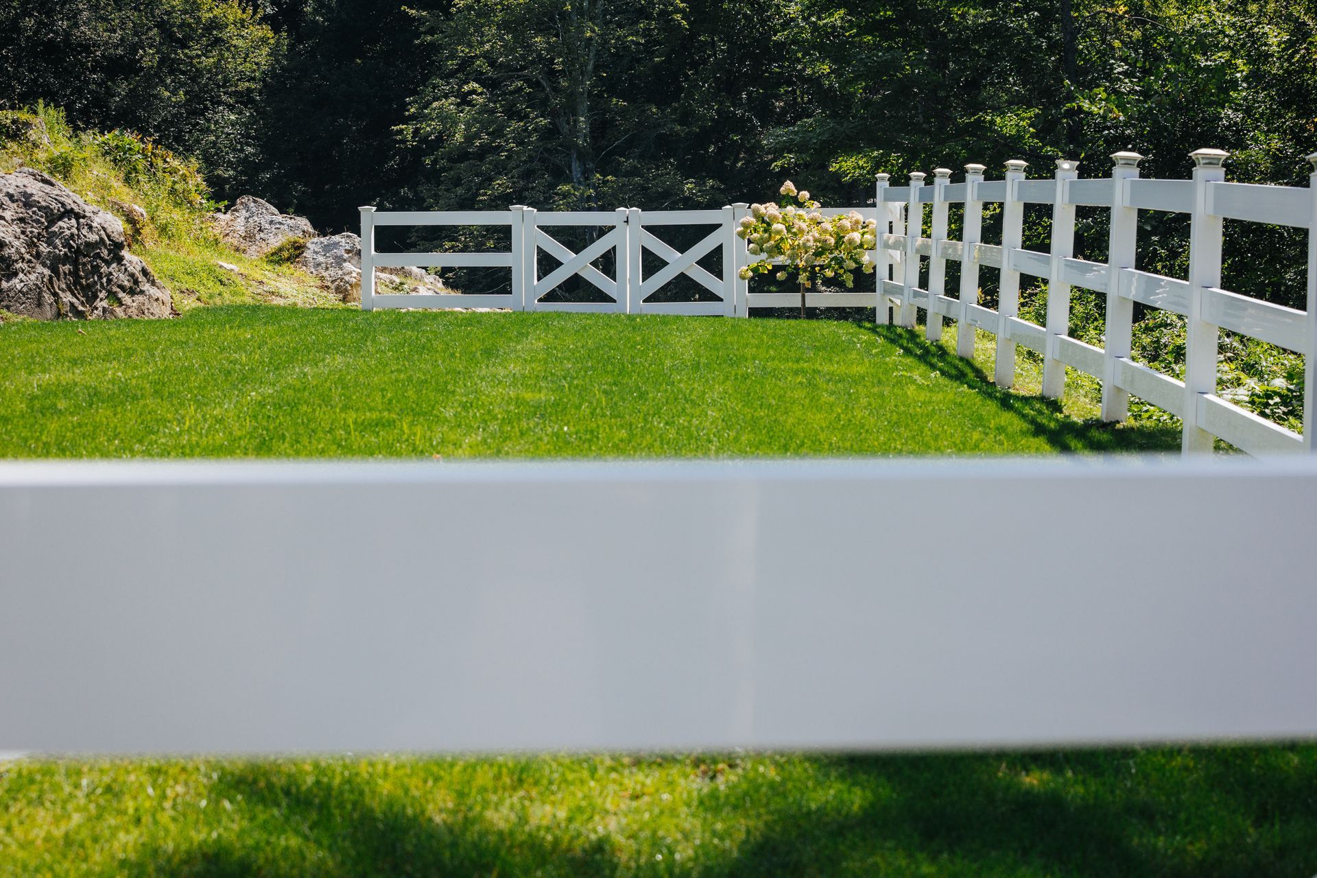 A white fence surrounds a lush green field.