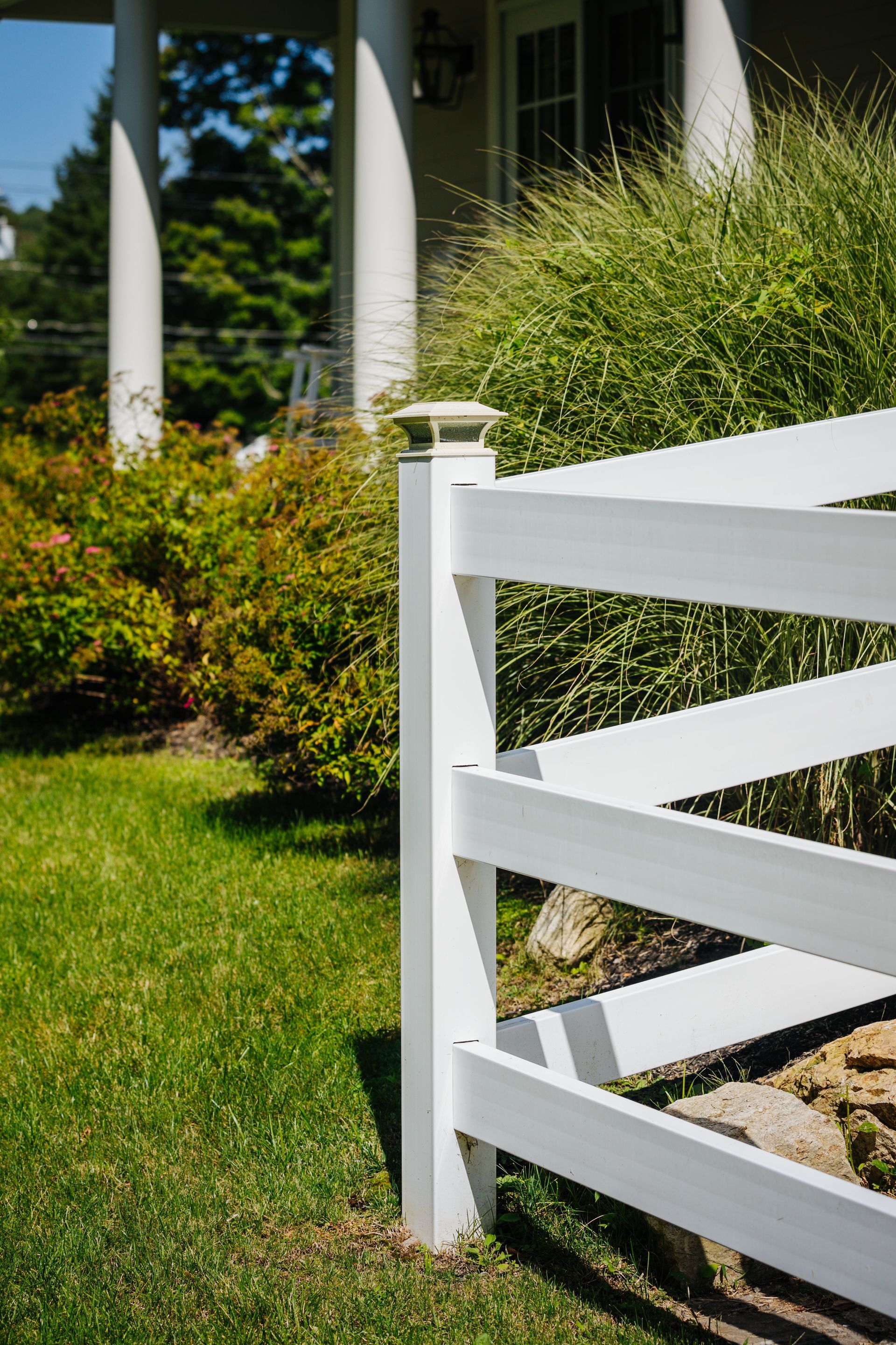 A white fence is sitting in the grass in front of a house.