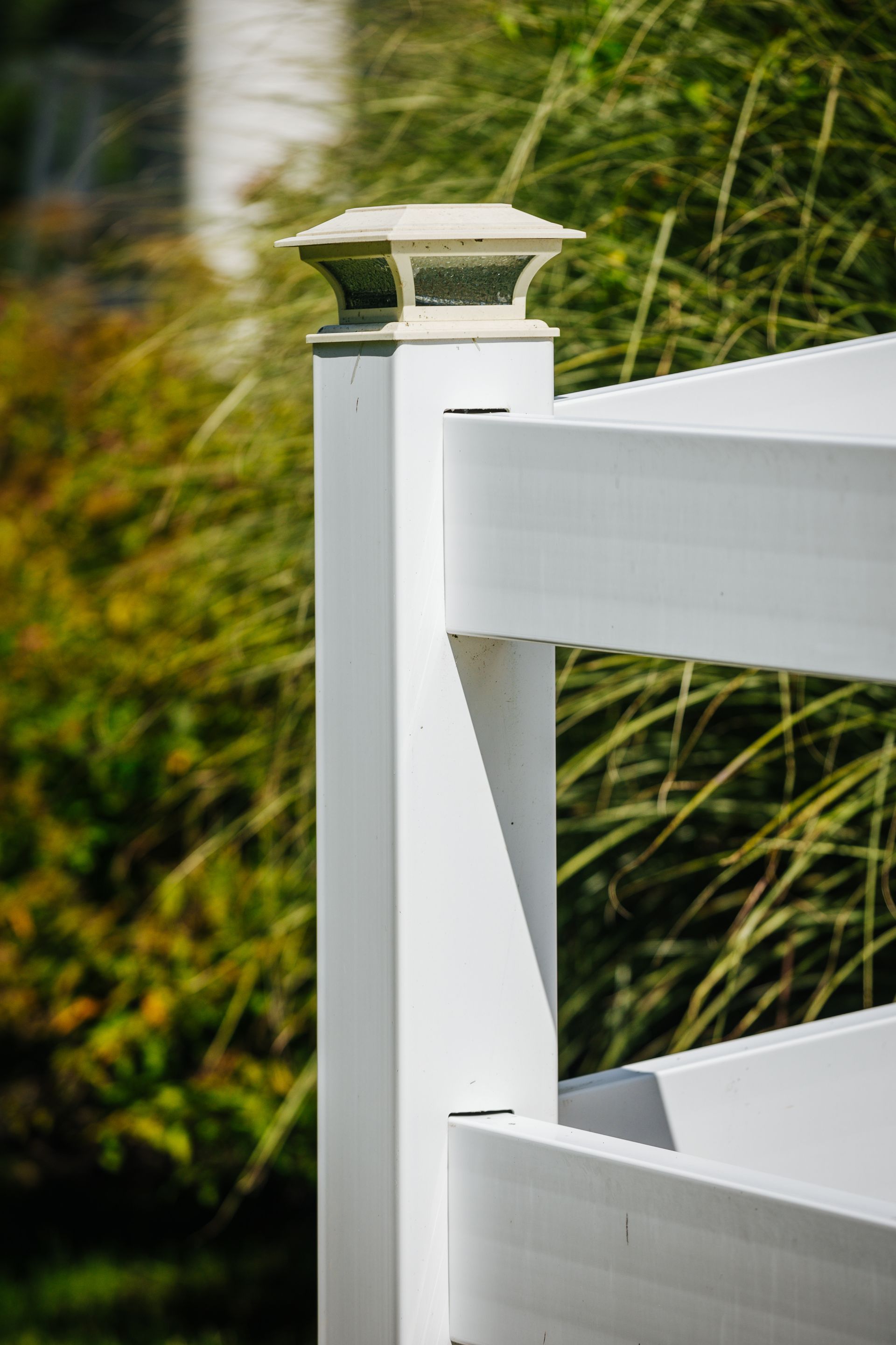 A close up of a white fence post with a light on top of it.