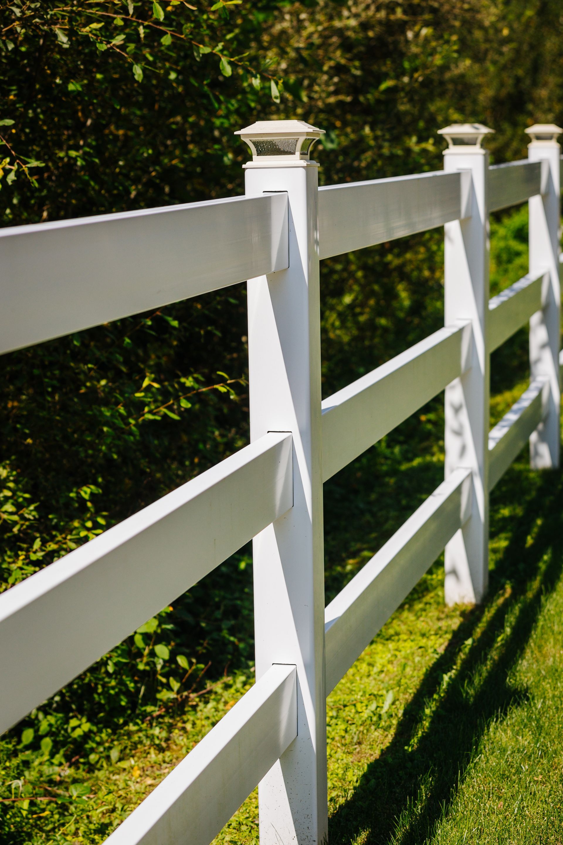 A white fence is surrounded by grass and trees.