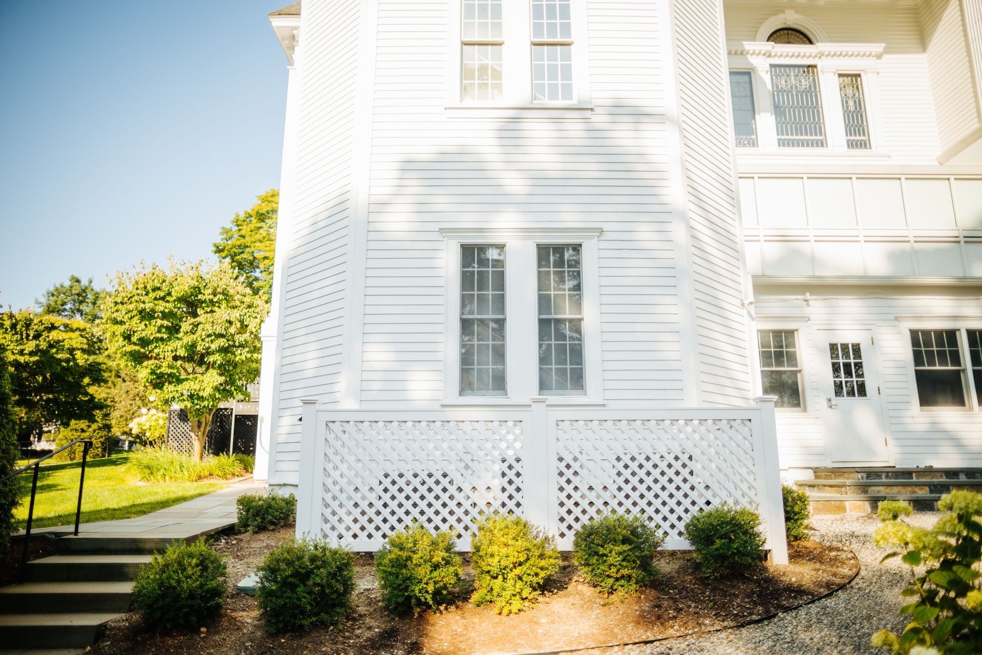 A white house with a fence and stairs in front of it.