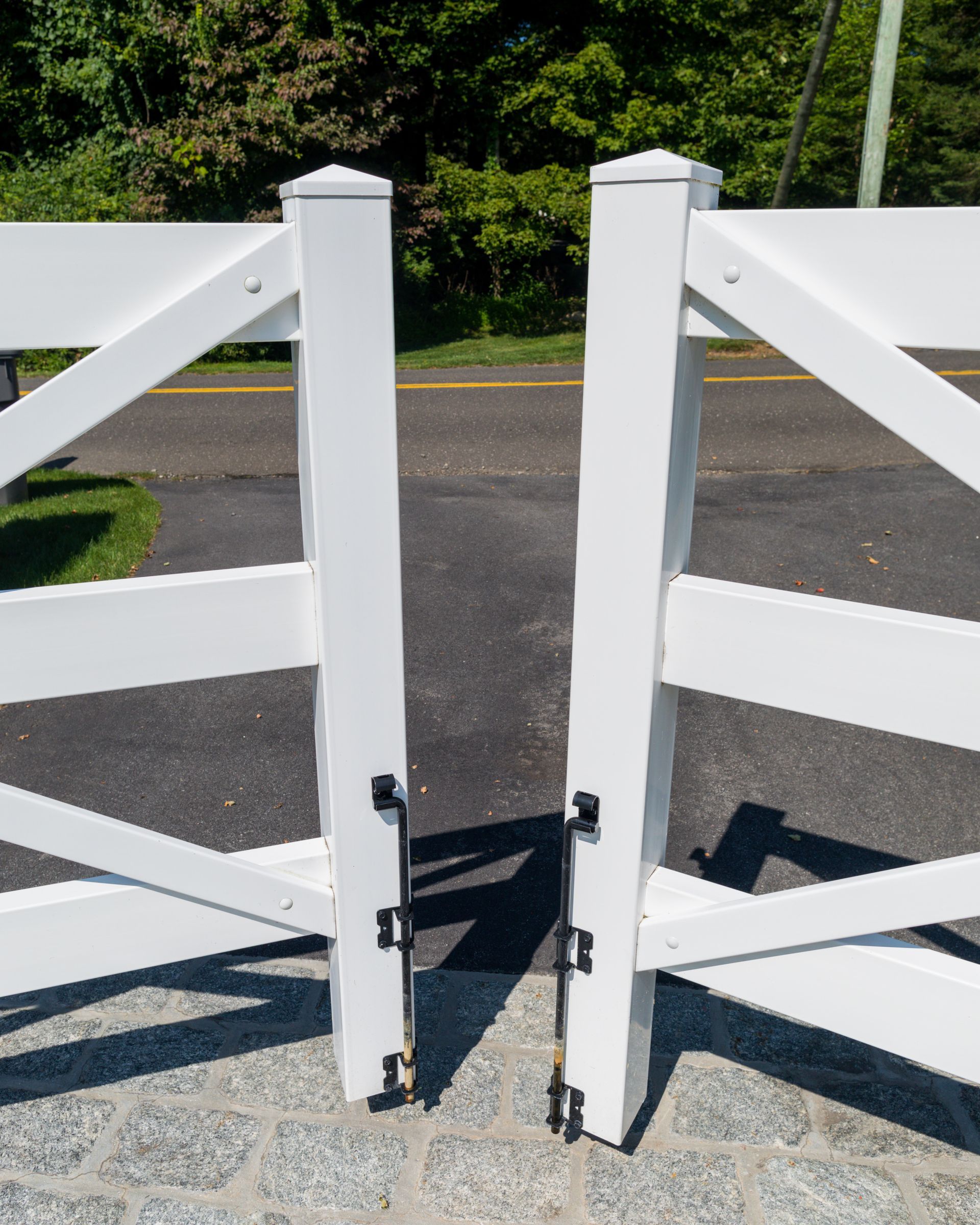 A white wooden fence is sitting on the side of a road.