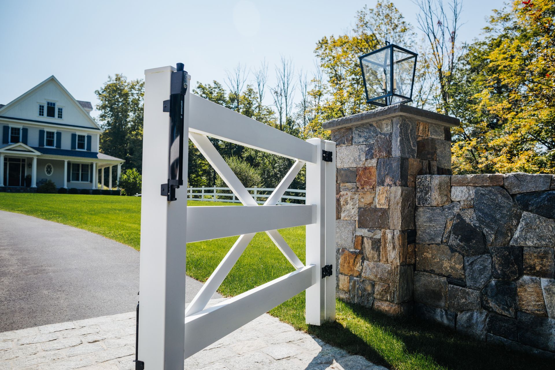 A white gate is open in front of a large house