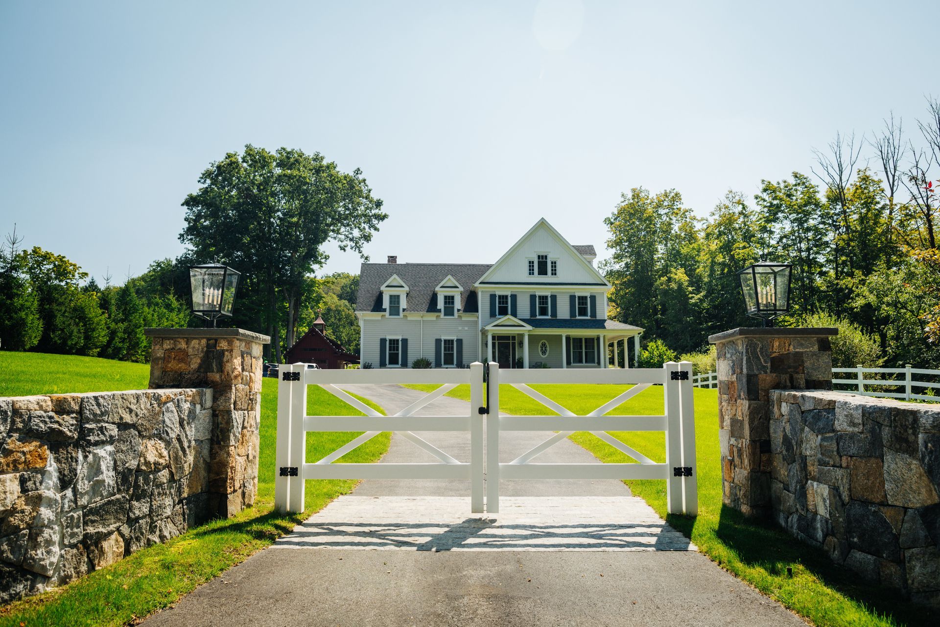 A large white house is behind a white gate