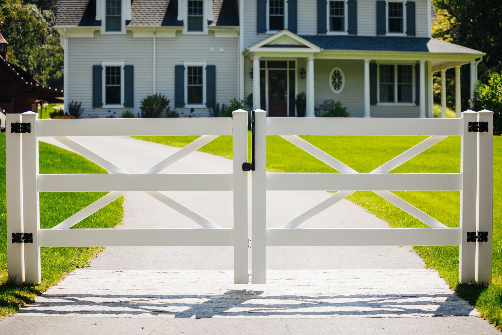 A white fence is in front of a white house.