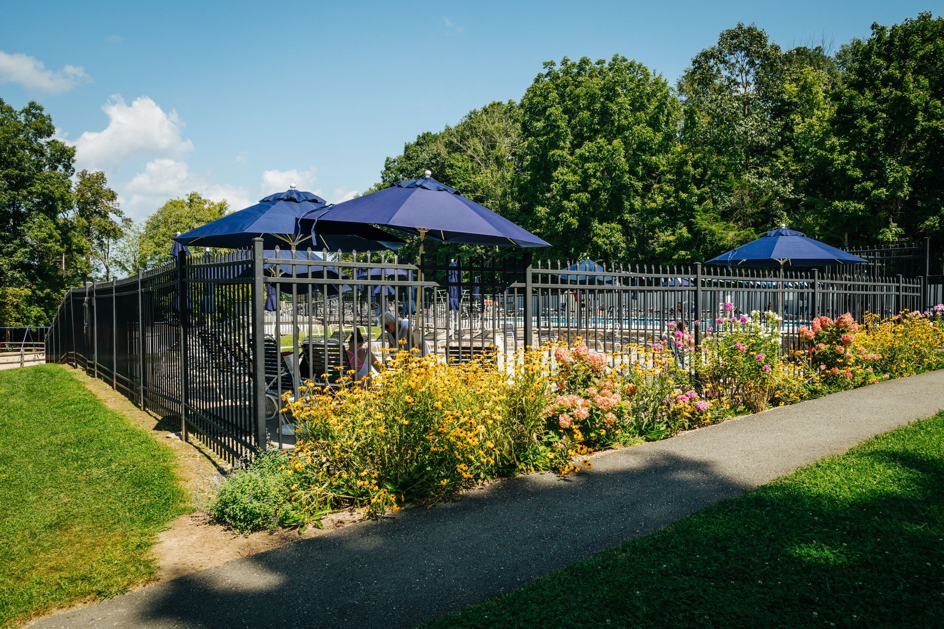 A fenced in area with tables and umbrellas in a park